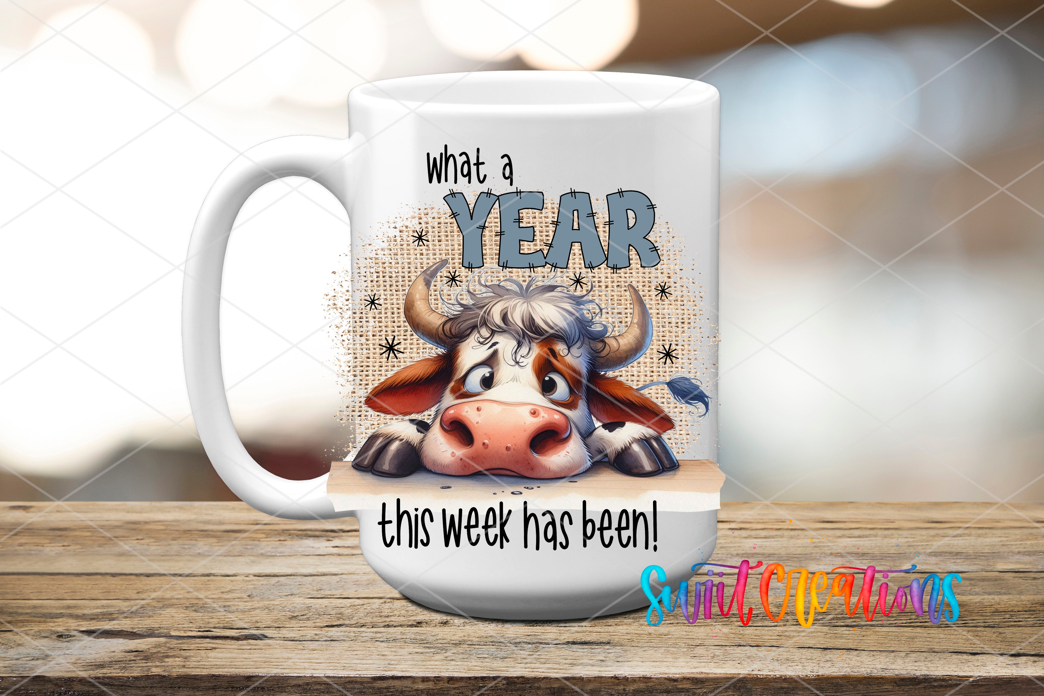 A white mug with a cartoon cow design and text that says "What a YEAR this week has been!"