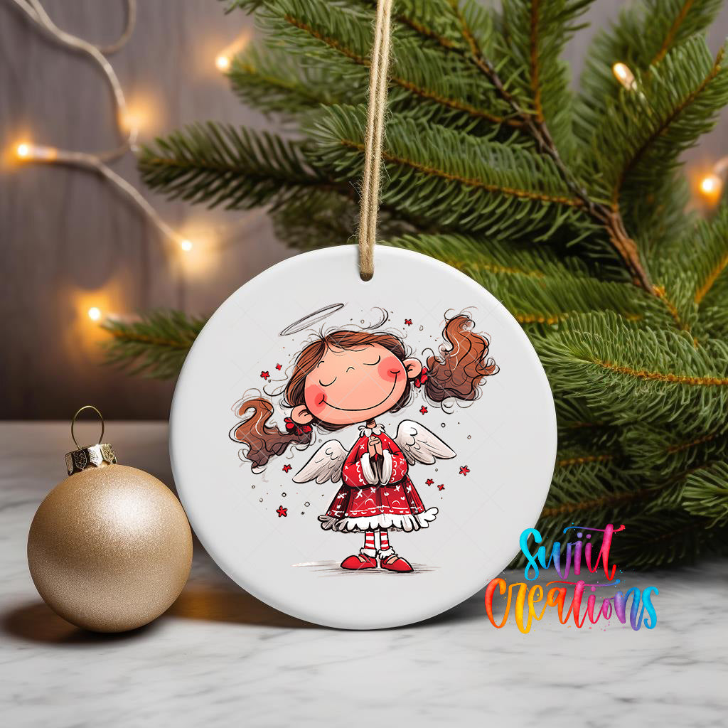 A white ceramic ornament featuring a smiling girl with angel wings, surrounded by Christmas lights and a pine tree.