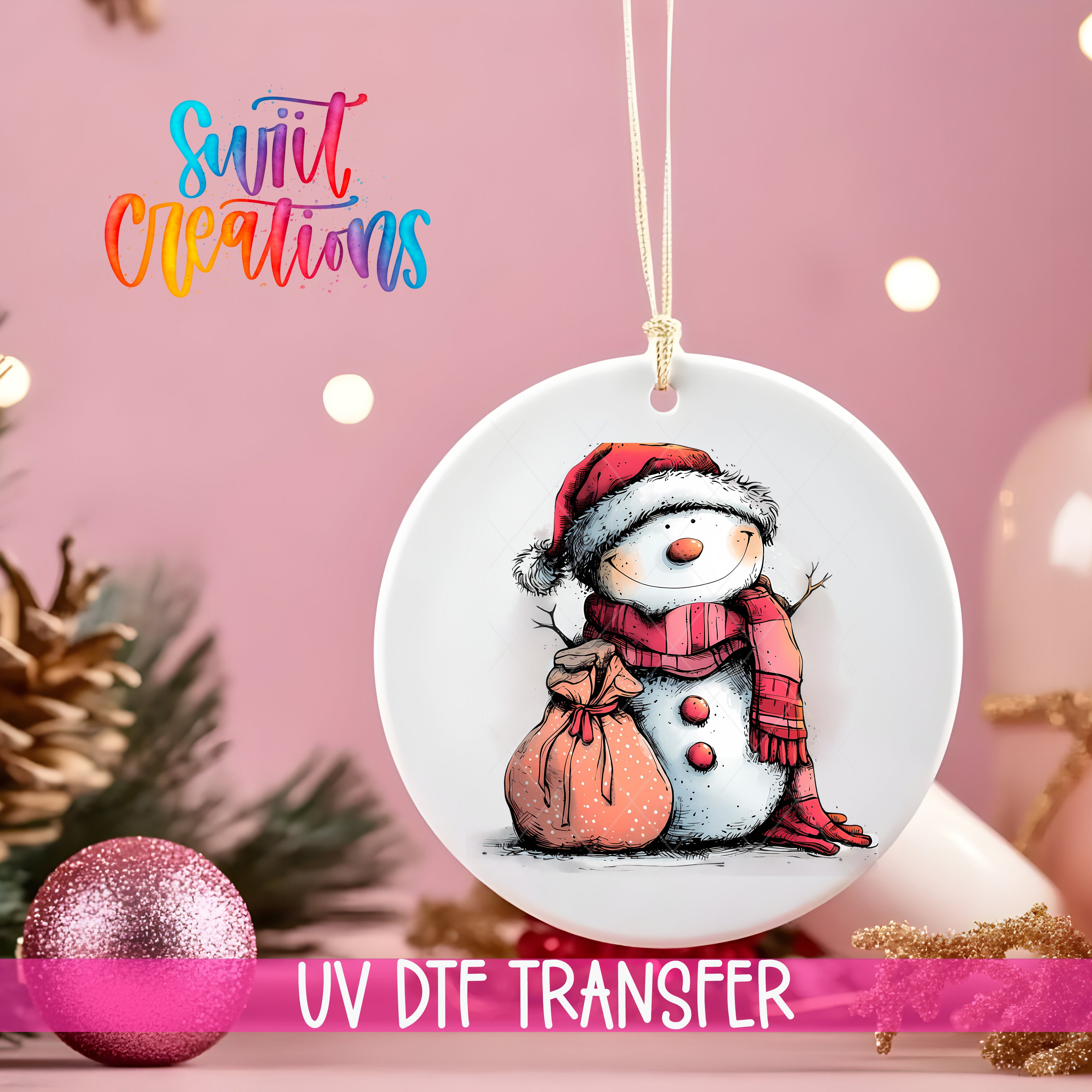 A white ceramic ornament with a snowman design, featuring a red scarf and hat, is hanging on a string against a pink background.