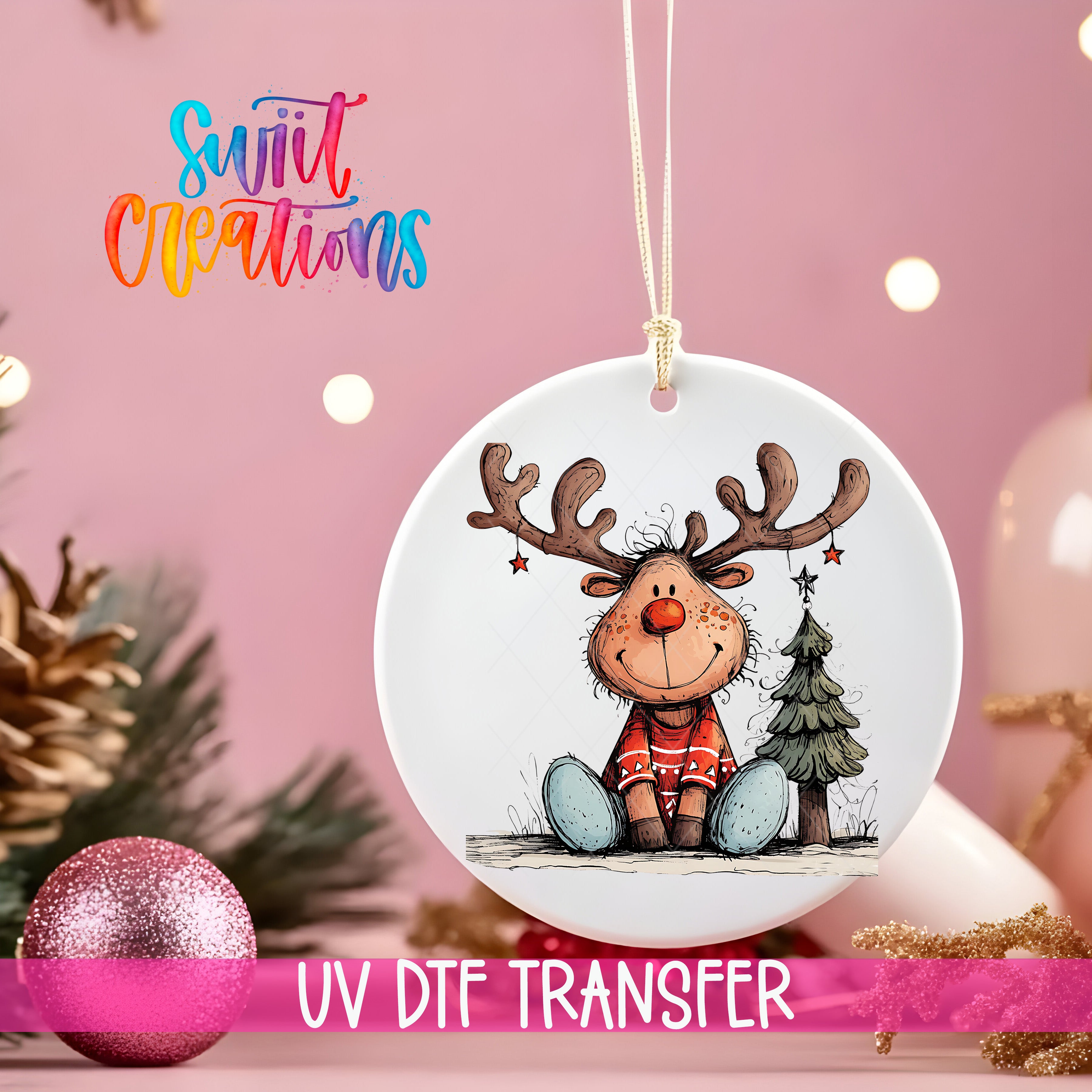 A white ornament with a cartoon reindeer and Christmas tree is hanging on a pink background, with a pink glitter ball and pine cones in the foreground.