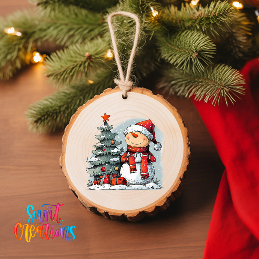 A wooden ornament featuring a snowman and a Christmas tree, with a star on top, hangs on a Christmas tree.
