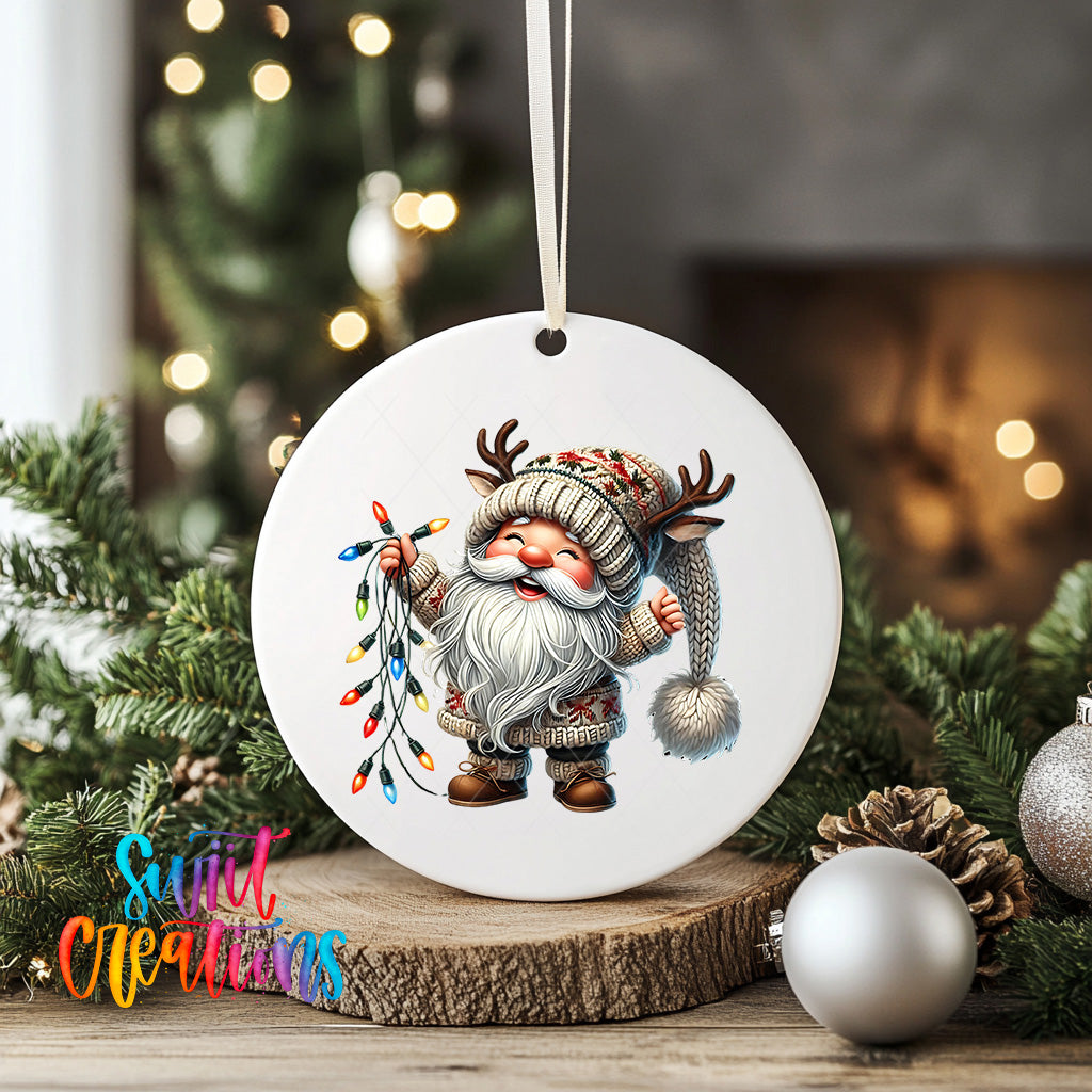 A white ceramic ornament featuring a gnome holding a string of colorful Christmas lights, surrounded by pine branches and ornaments.