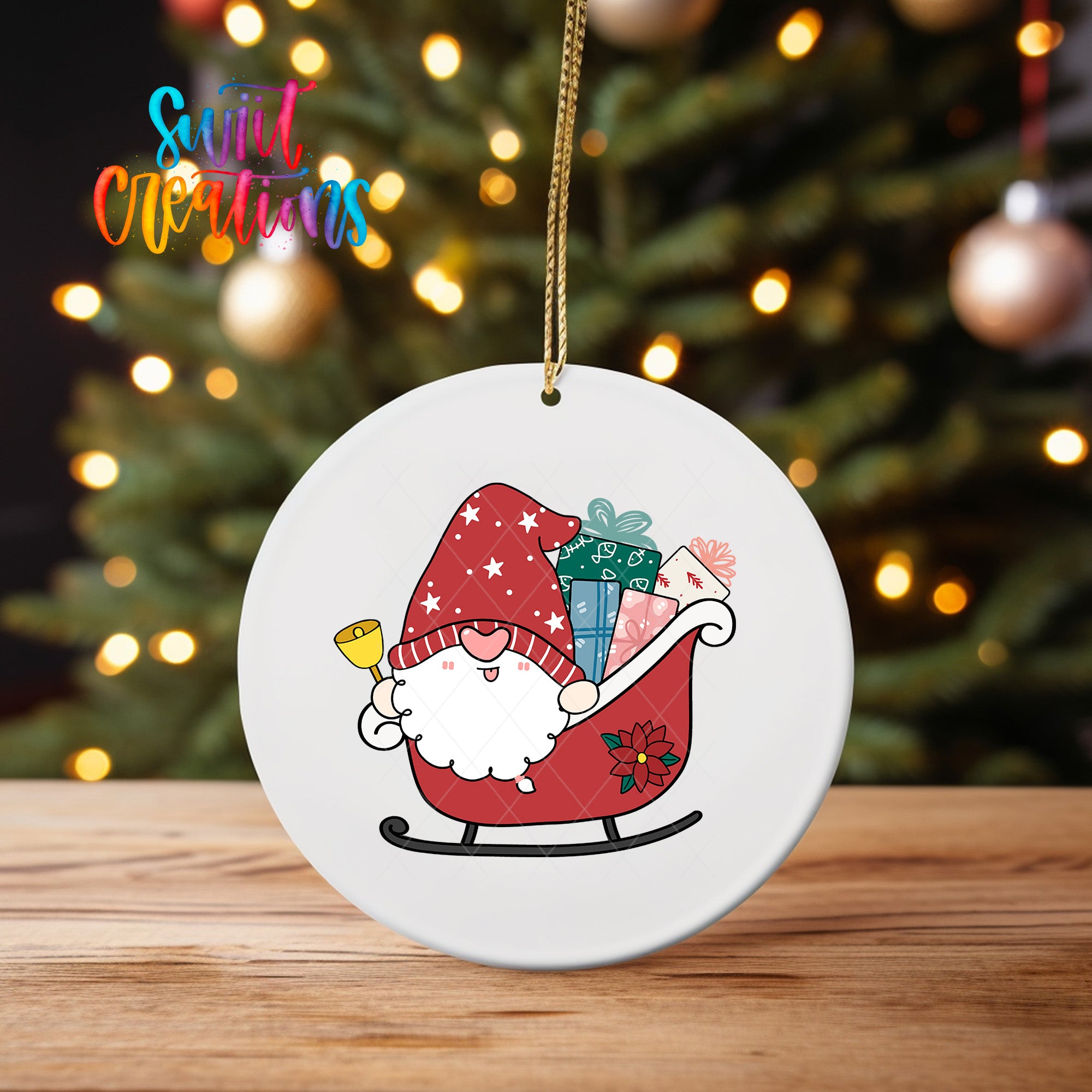 A white ornament featuring a cartoon gnome riding a sled with presents and a bell, set against a blurred background of Christmas lights.