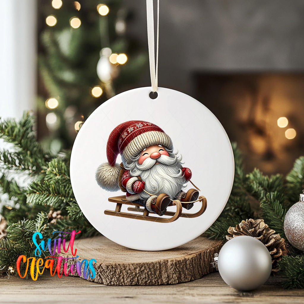 A white ceramic ornament featuring a smiling Santa Claus on a sled, surrounded by Christmas decorations and greenery.