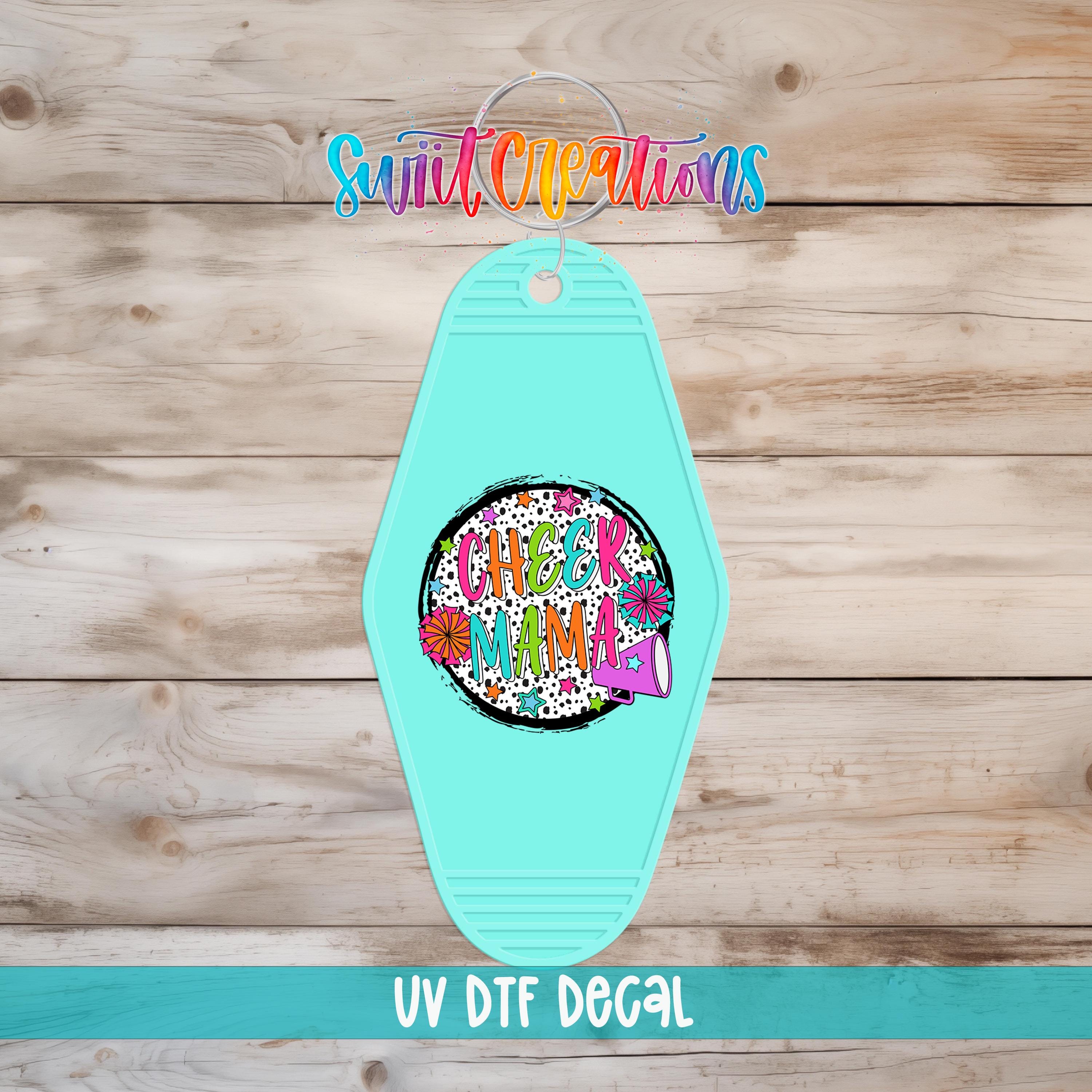 A turquoise keychain with a colorful graphic design and text, placed on a wooden surface.
