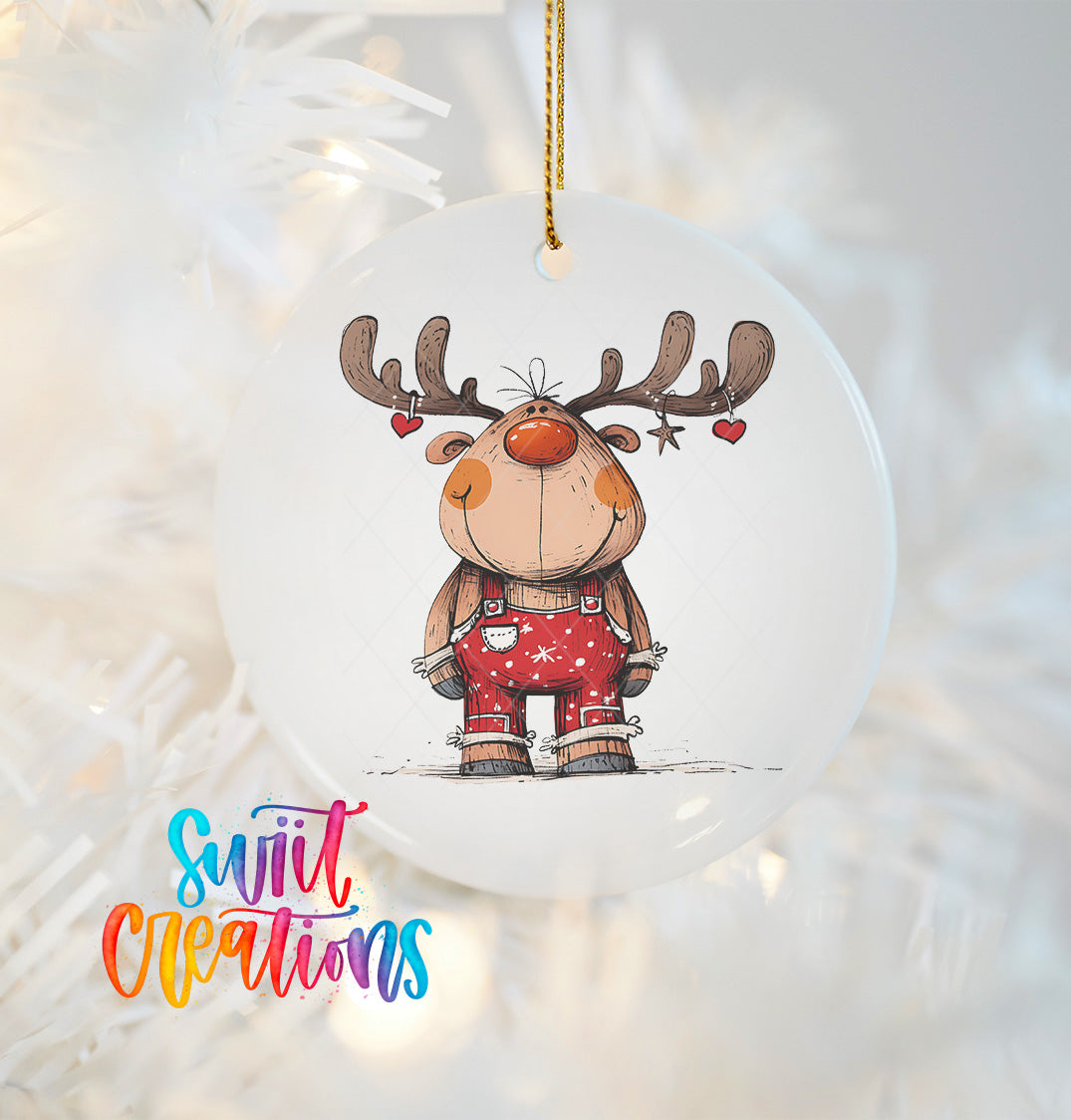 A white ornament featuring a cartoon reindeer with antlers and a red nose, hanging on a Christmas tree.