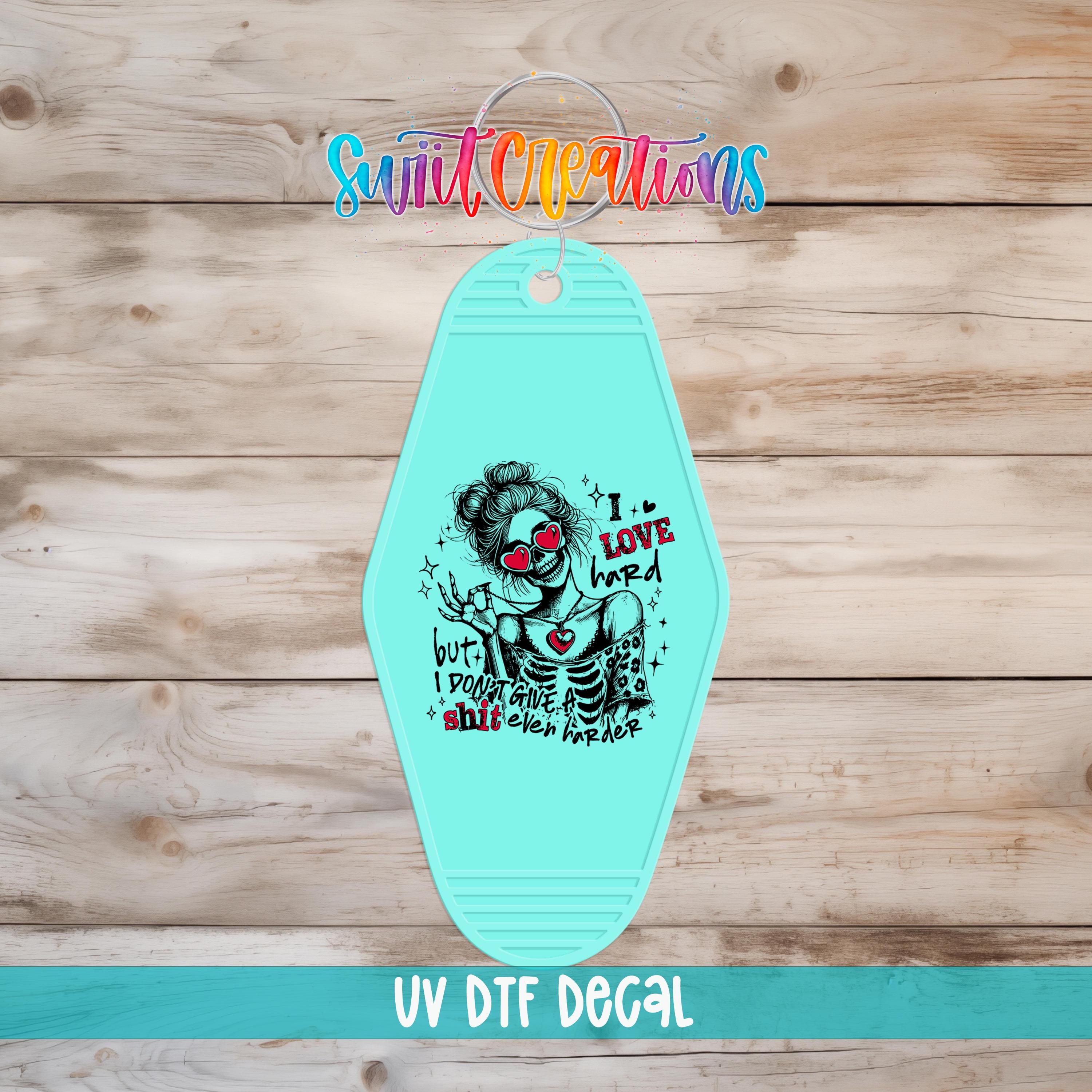 A turquoise keychain with a graphic design featuring a skeleton wearing sunglasses and the text "I LOVE hard" printed on it.