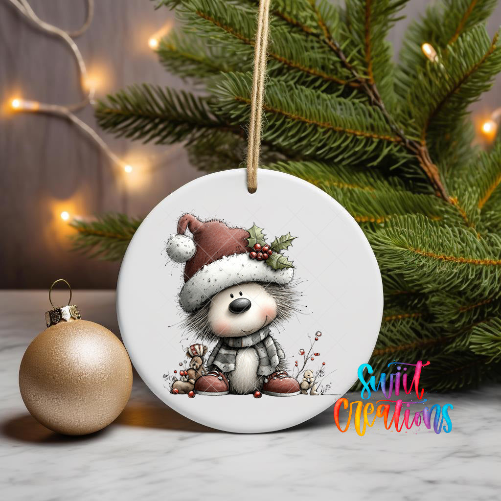 A white ceramic ornament featuring a cartoon image of a dog wearing a Santa hat and scarf, sitting on a Christmas tree branch with other ornaments and lights in the background.