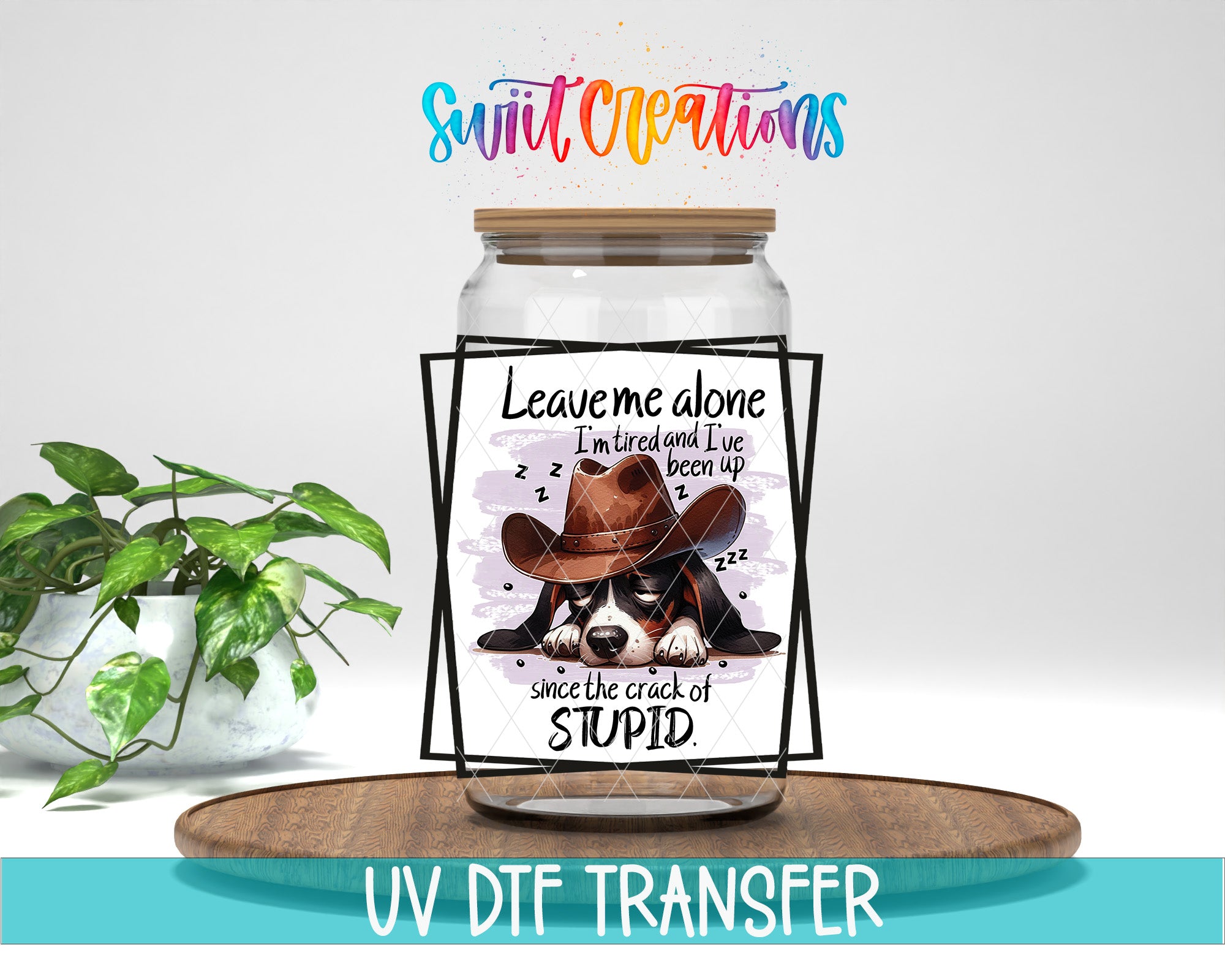 a jar with a label that says "Leave me alone I'm tired and I've been up since the crack of stupid" along with a cartoon image of a dog wearing a cowboy hat. The jar is placed on a wooden surface, and there is a potted plant in the background.