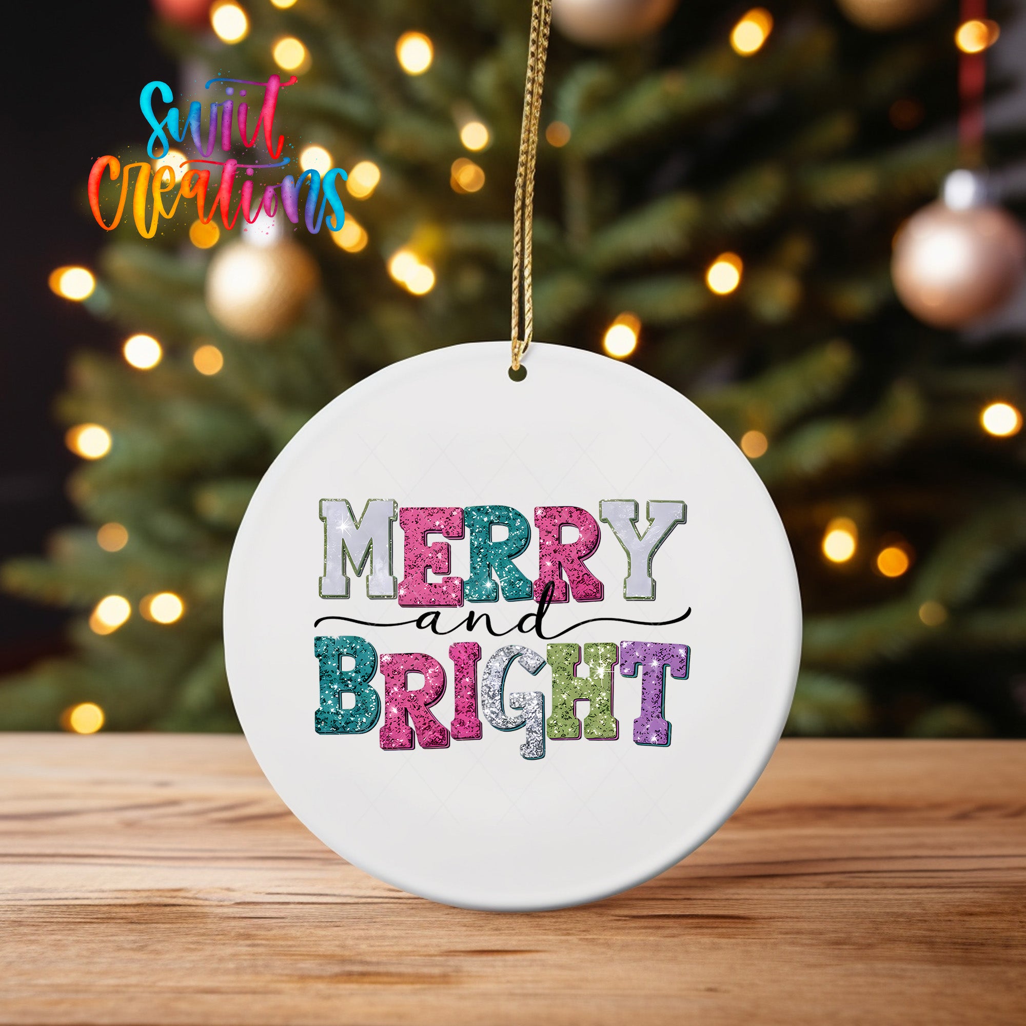 A white ceramic ornament with the text "MERRY AND BRIGHT" in colorful letters hangs from a string against a blurred background of a Christmas tree with twinkling lights.