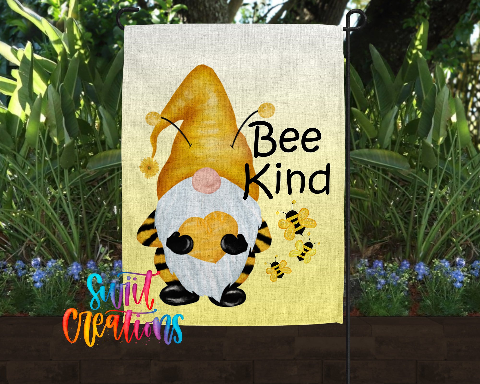 A garden flag featuring a gnome with a yellow hat and a bee on its back, surrounded by flowers and greenery.