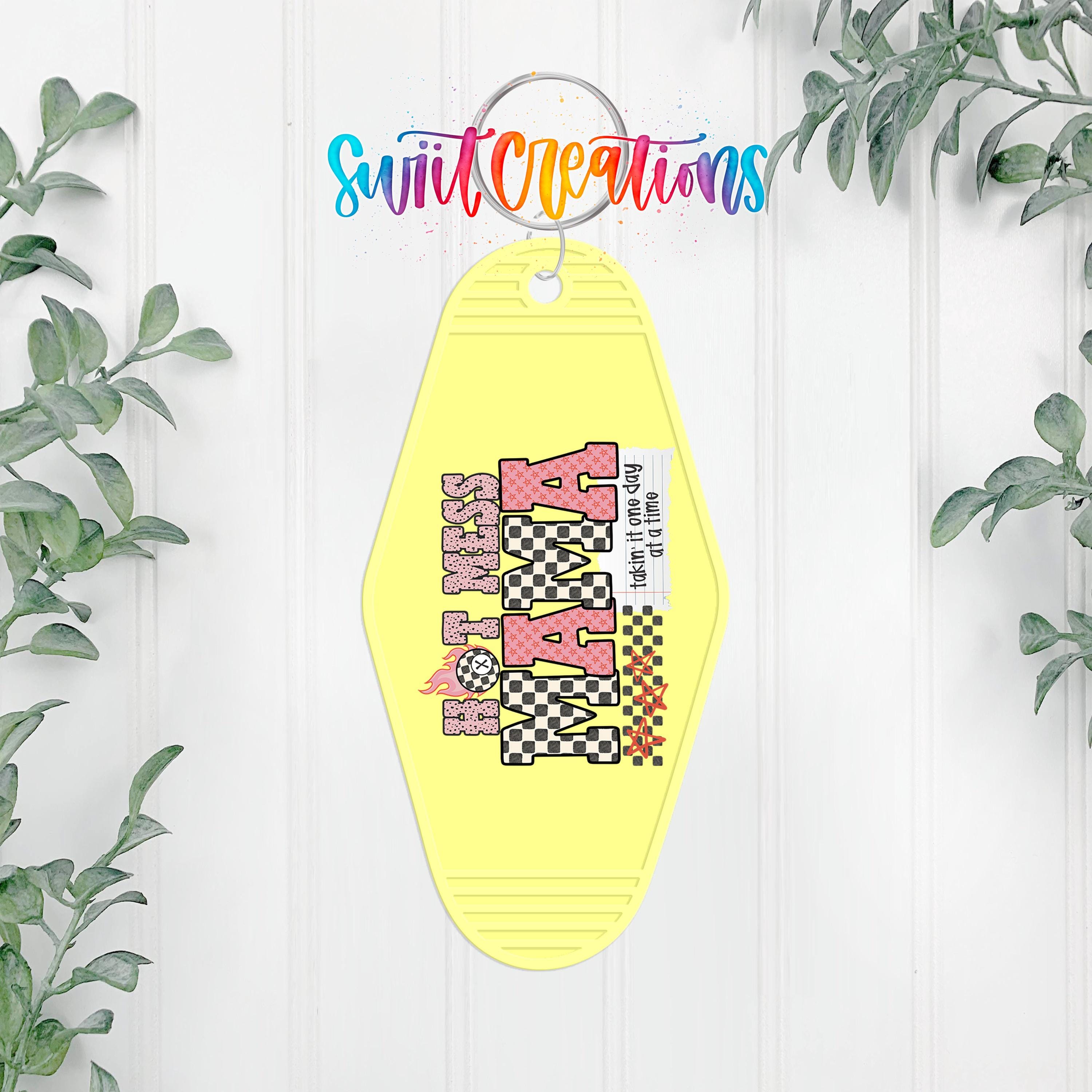 A yellow keychain with a checkered pattern and the word "Mama" printed on it, hanging on a white wall.