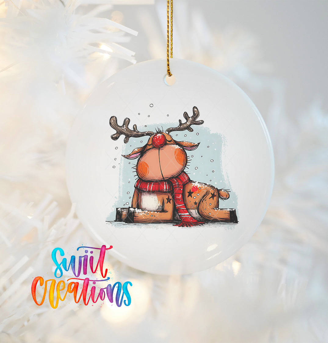 A white ornament with a cartoon image of a reindeer wearing a red scarf and sitting on a snowy surface.