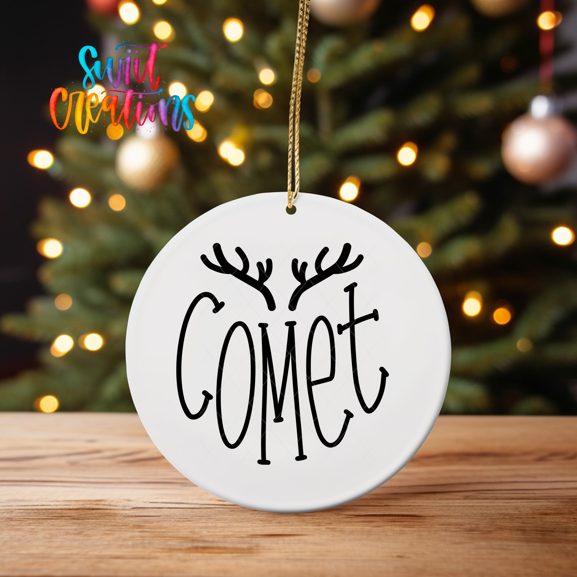A white ornament with the word " Comet" written on it, hanging from a string.