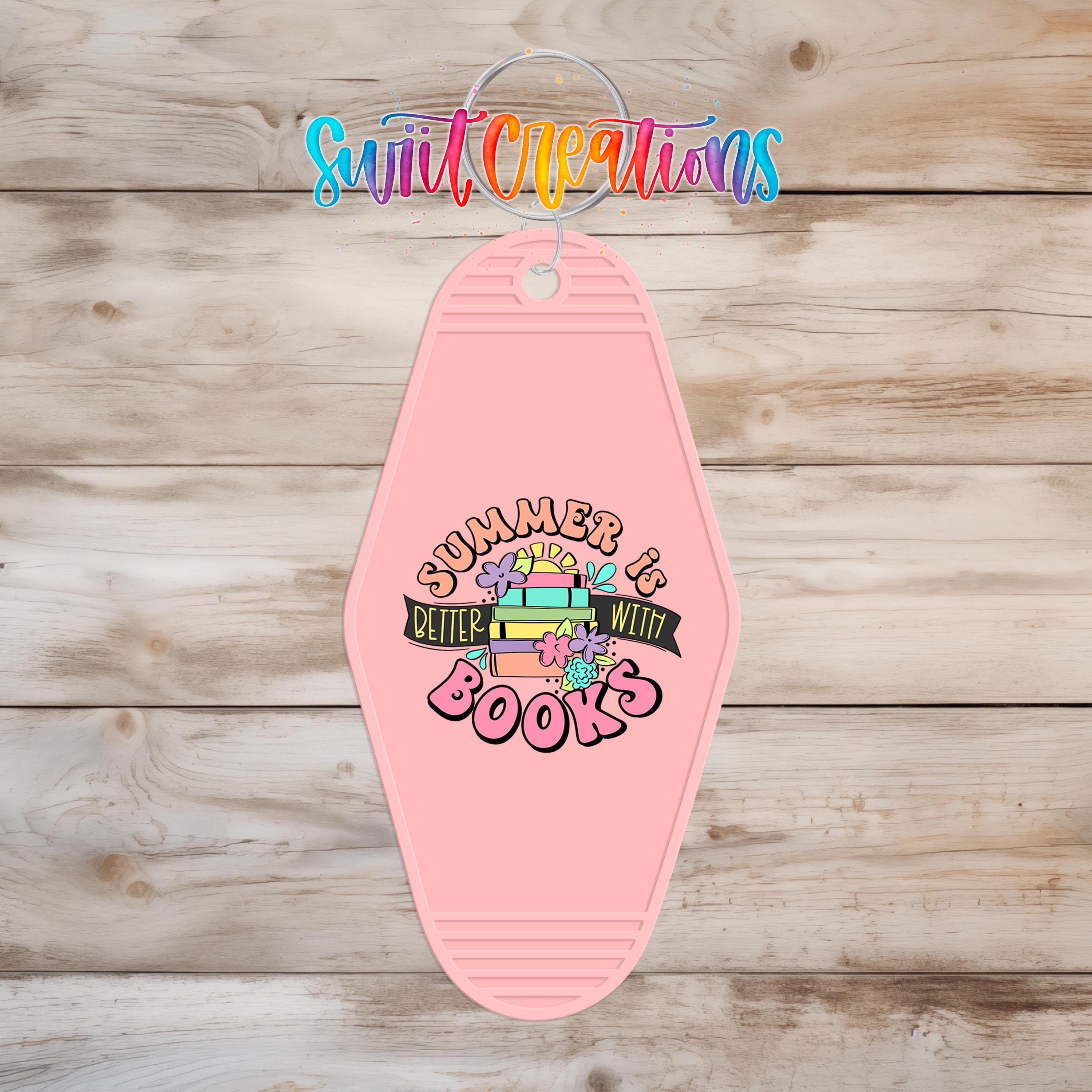 A pink keychain with a colorful design and text that says "Summer is better with books".