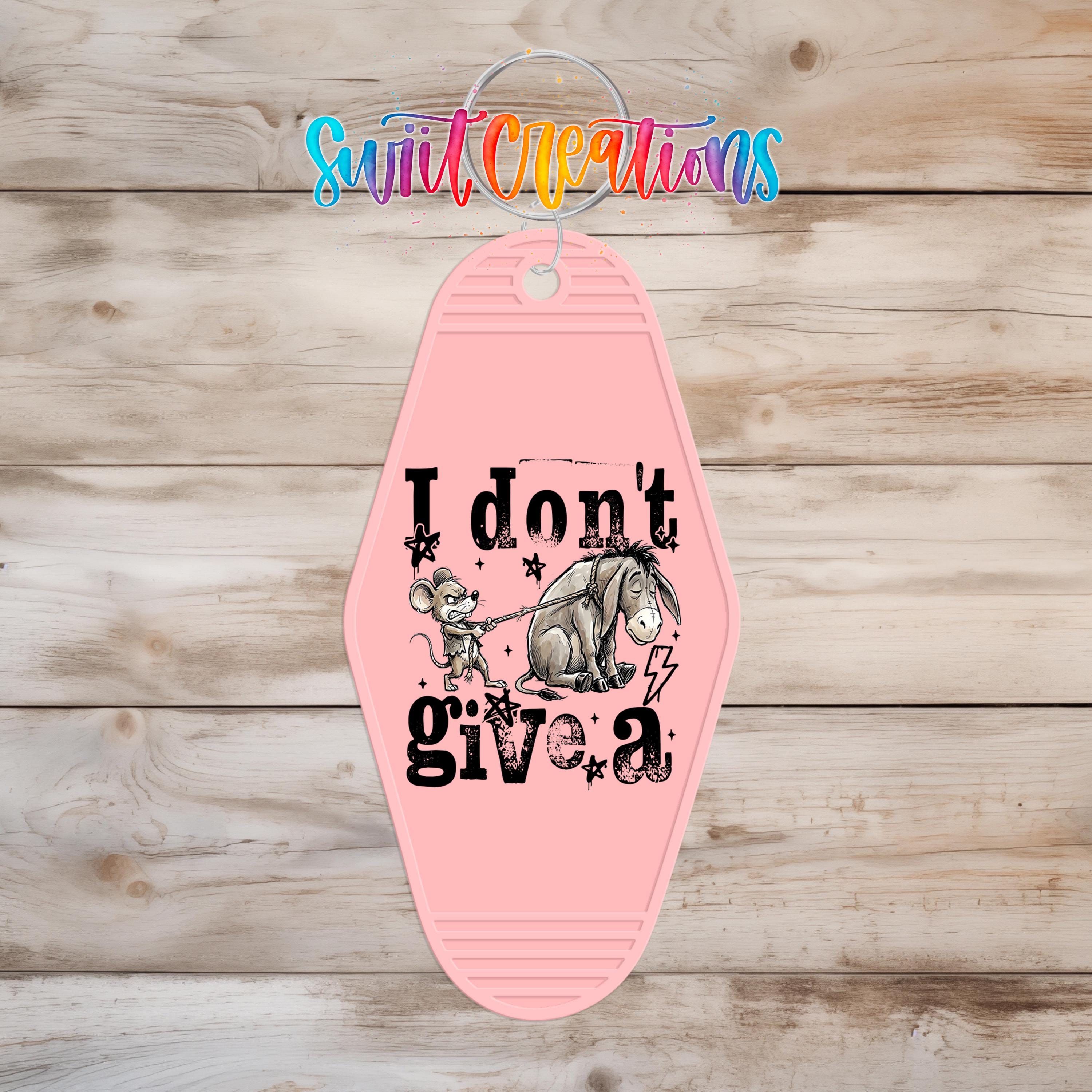A pink keychain with a cartoon image of Eeyore and the text "I don't give a" printed on it.