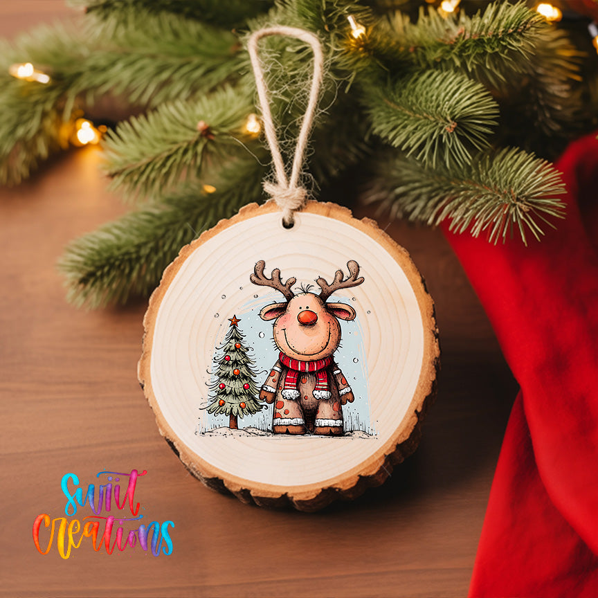 A wooden ornament featuring a cartoon reindeer is hanging on a Christmas tree, with a small Christmas tree and twinkling lights visible in the background.