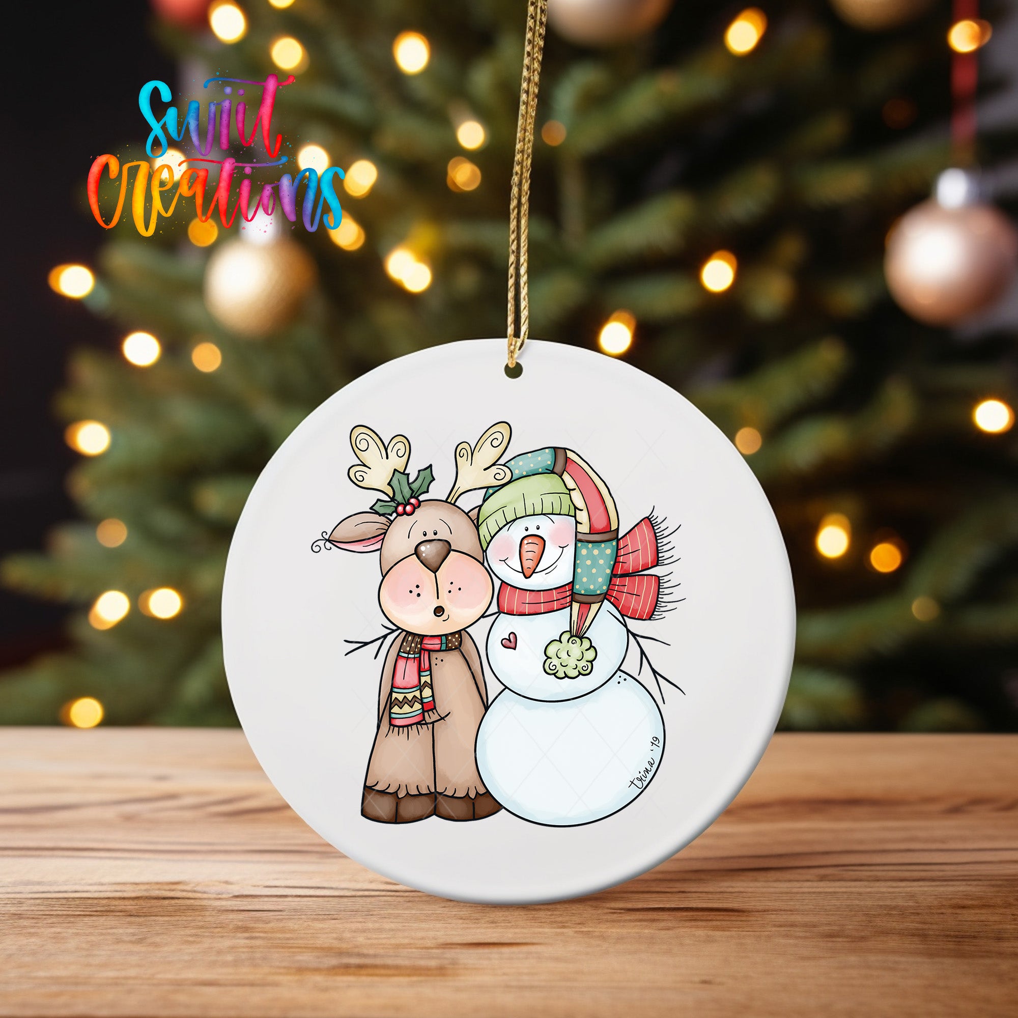 A white ceramic ornament featuring a cartoon illustration of a deer and a snowman, with Christmas lights in the background.