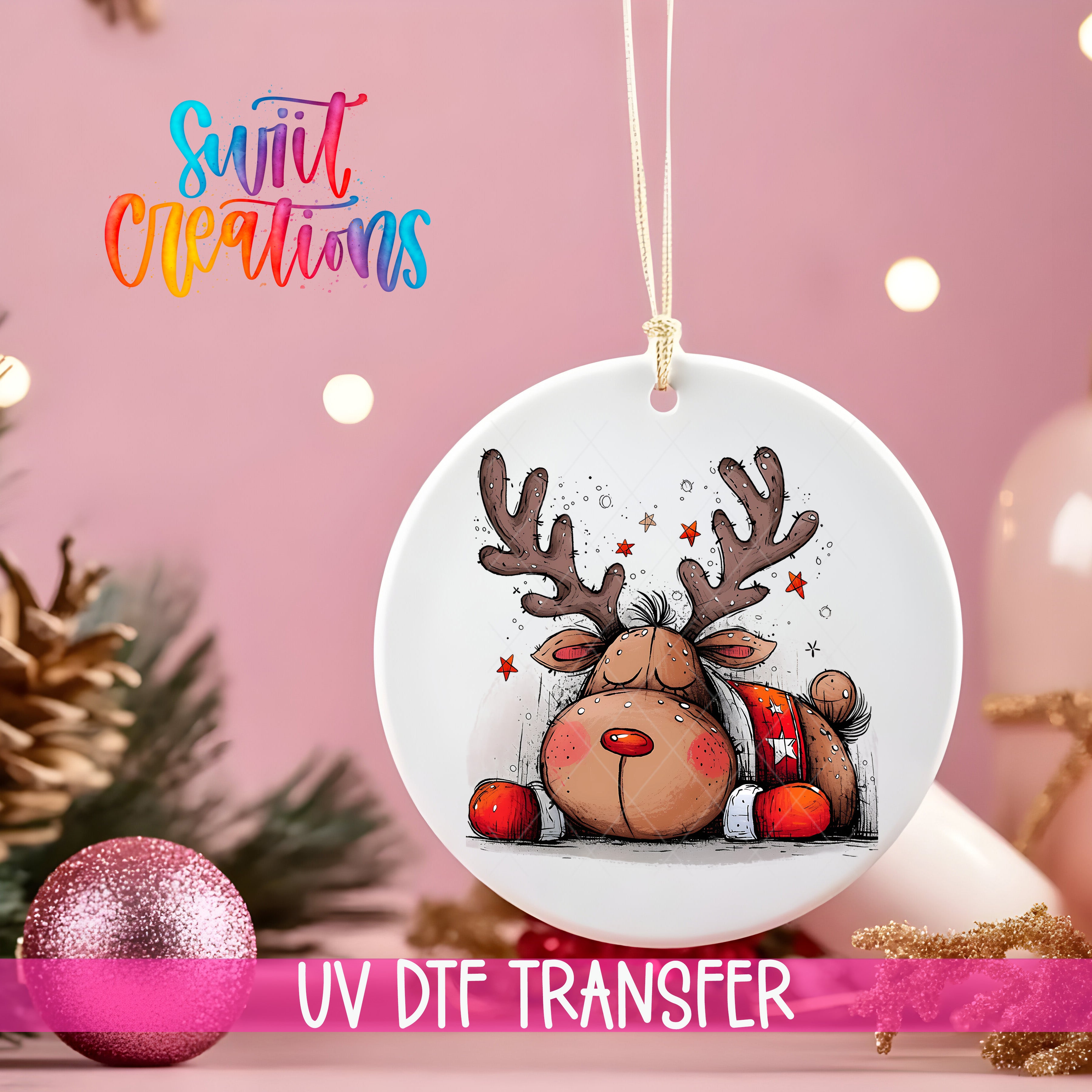 A white ornament with a cartoon reindeer and Christmas decorations is hanging on a string, with a pink background and some lights.