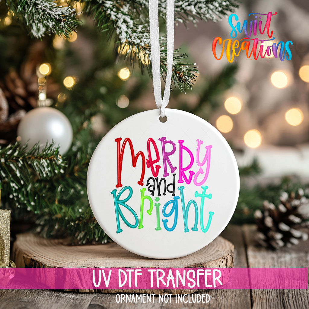A white ceramic ornament with the text "Merry and Bright" in colorful letters hangs from a Christmas tree.