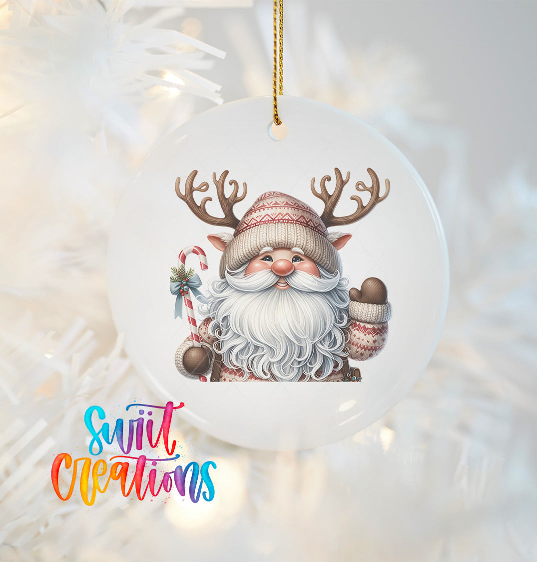 A white ornament featuring a smiling Santa Claus with antlers and a bow, hanging on a Christmas tree.