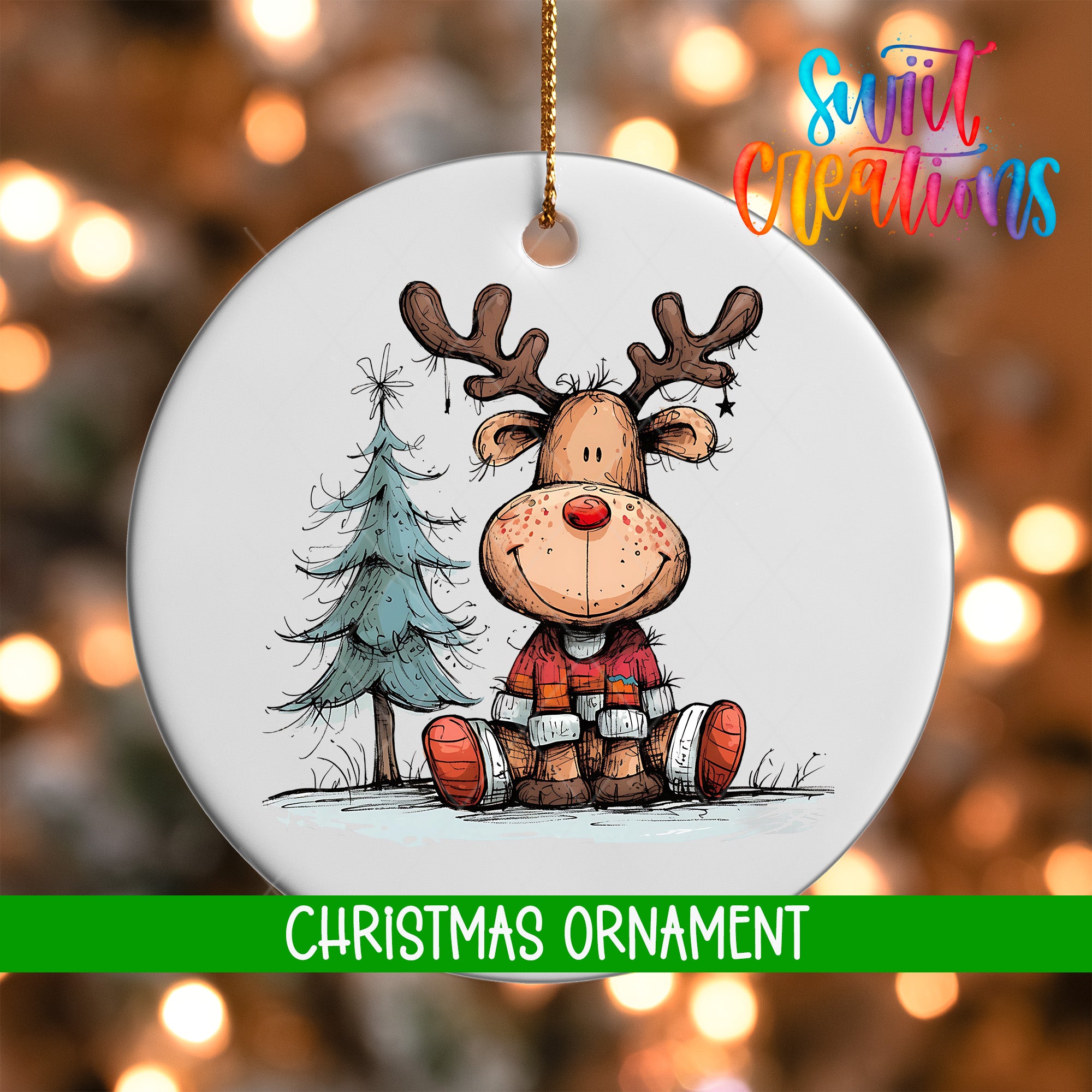 A white Christmas ornament featuring a cartoon reindeer sitting next to a Christmas tree.