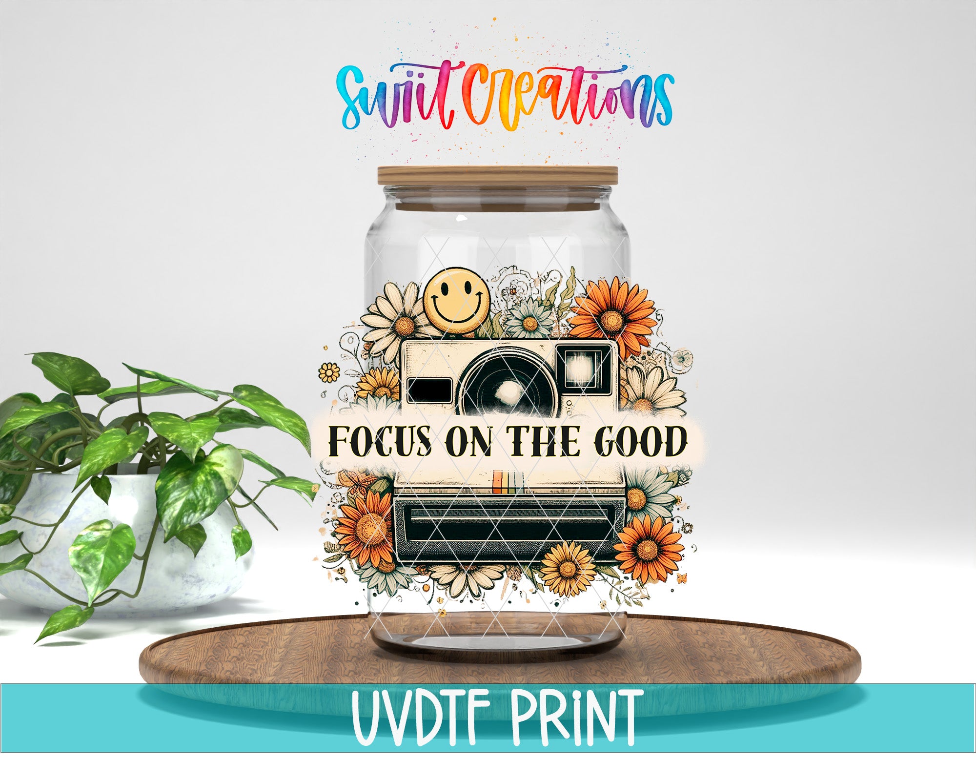 a glass jar with a camera and flowers, along with the text "Focus on the good" and "Swift Creations" written above it. The jar is placed on a wooden surface, and there is a potted plant in the background.