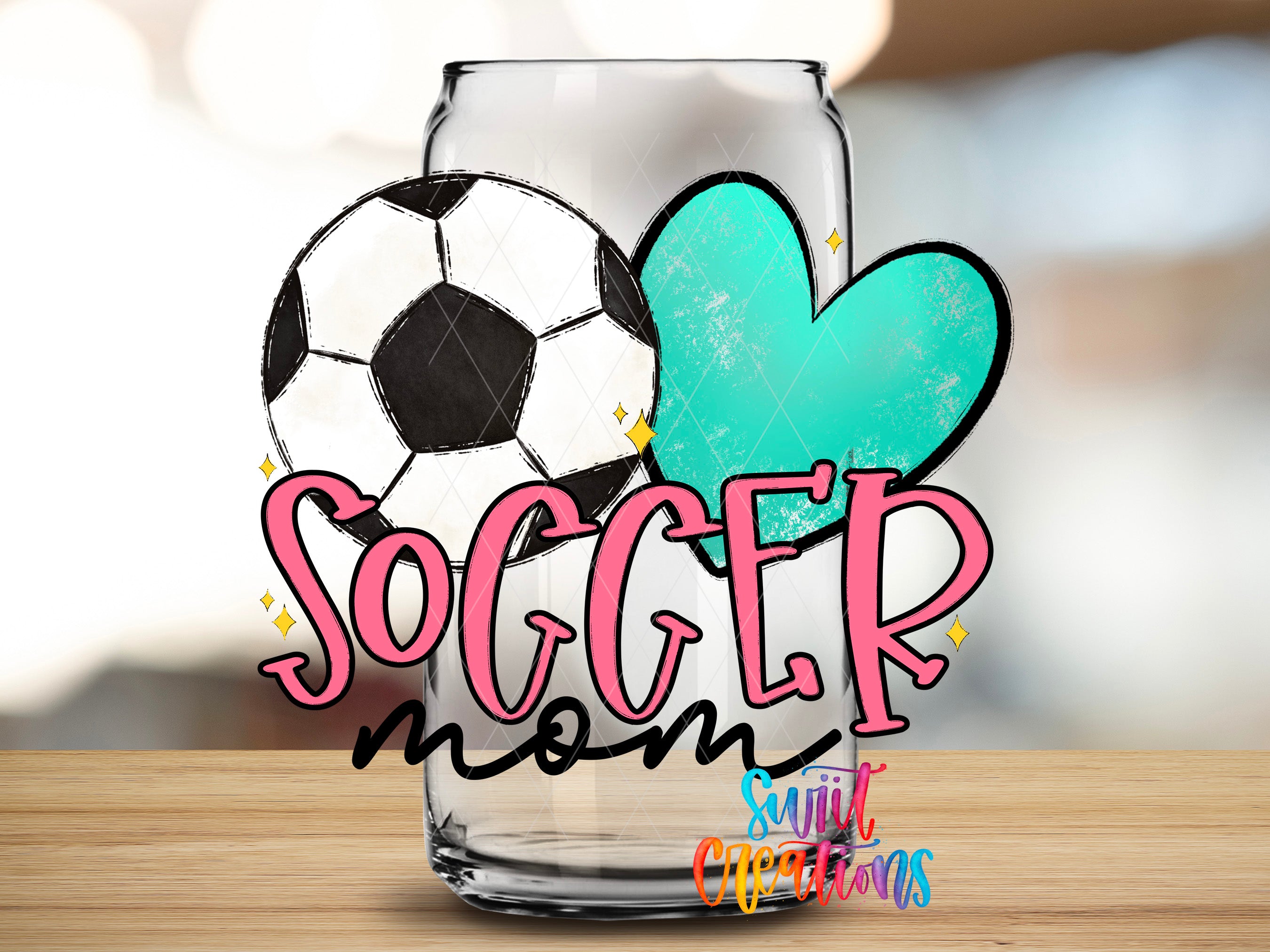 A glass can with a soccer ball and a heart-shaped cutout in the center, along with the text "SOCCER mom" and "Suitcase Creations" written on it.