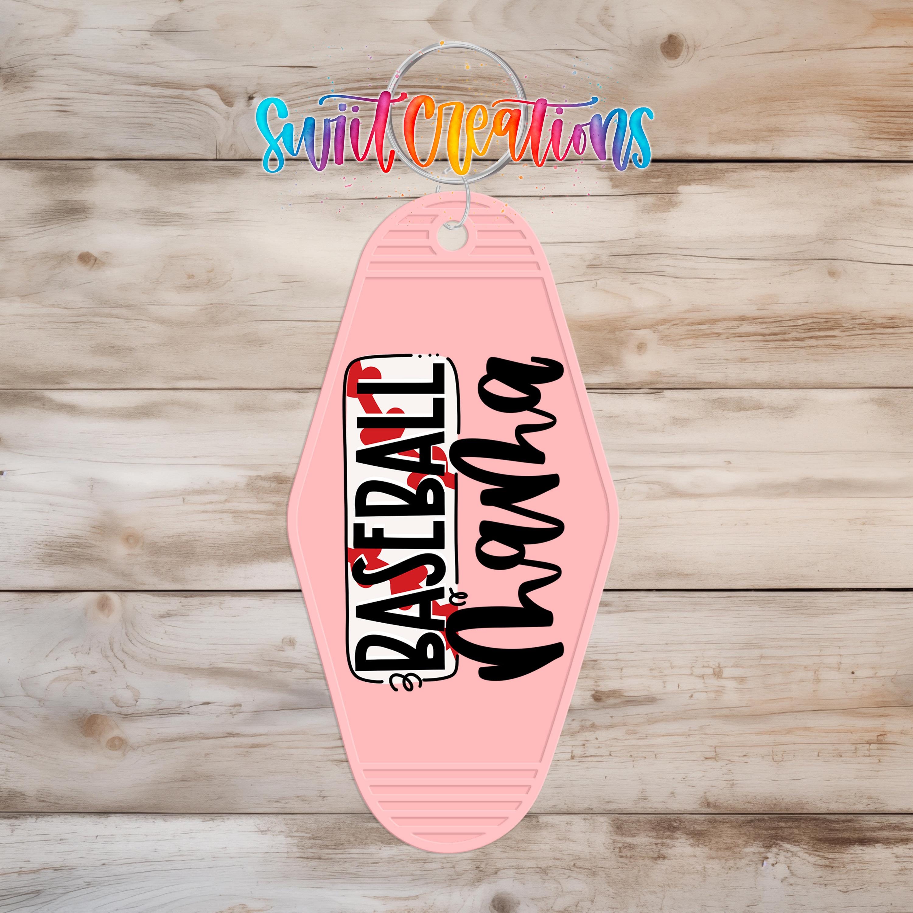 A pink keychain with the text "BASEBALL" printed on it, hanging on a wooden surface.