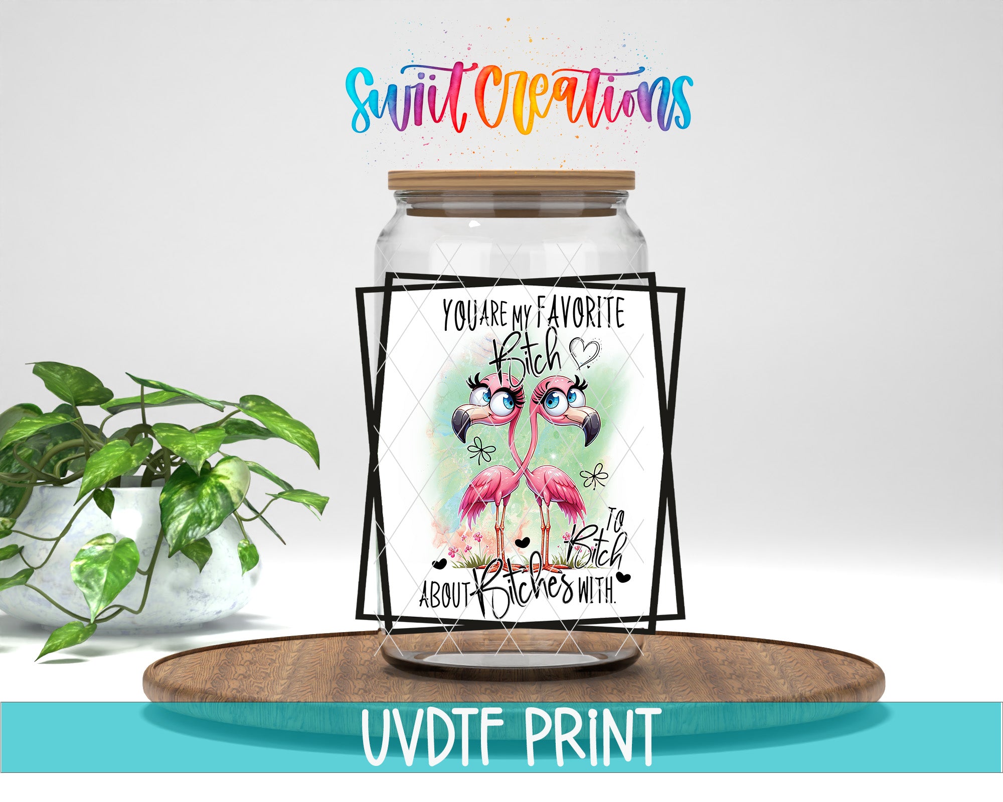 A glass jar with a label featuring a pair of pink flamingos, accompanied by a message that says "You are my favorite flambee". The jar is placed on a wooden tray, and there is a potted plant in the background.