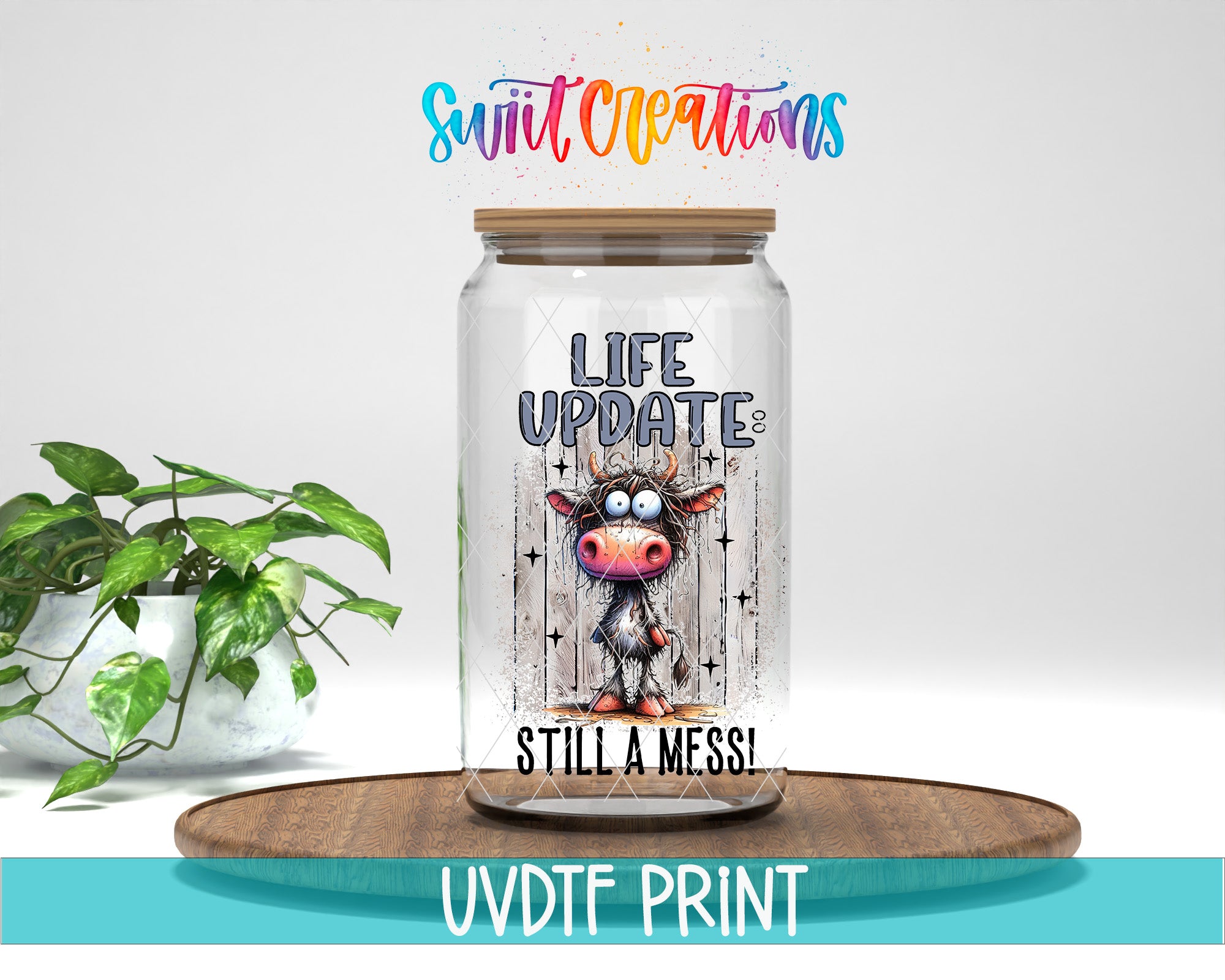 a glass jar with a cartoon cow design, placed on a wooden surface. The jar has a label that reads "LIFE UPDATES STILL A MESS!" The background of the image is white, and there is a plant visible on the left side.