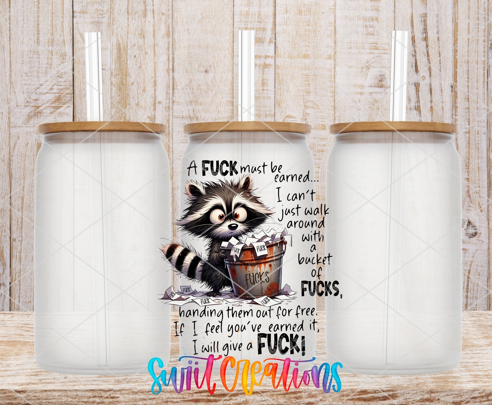 A F*ck Must Be Earned Raccoon UV DTF transfer applied to a clear glass can set from Swiit Creations