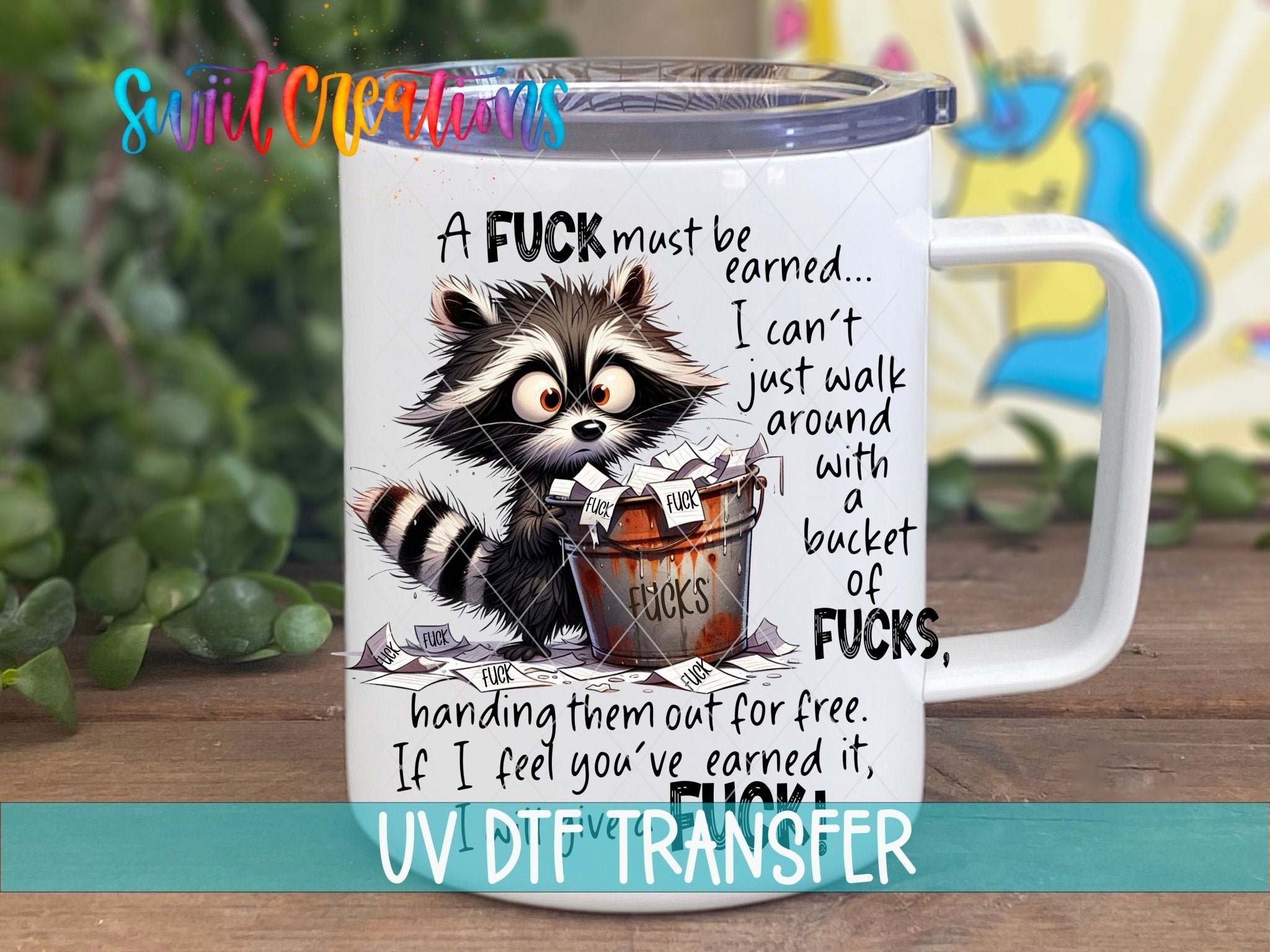 A F*ck Must Be Earned Raccoon UV DTF transfer displayed on a white coffee mug from Swiit Creations