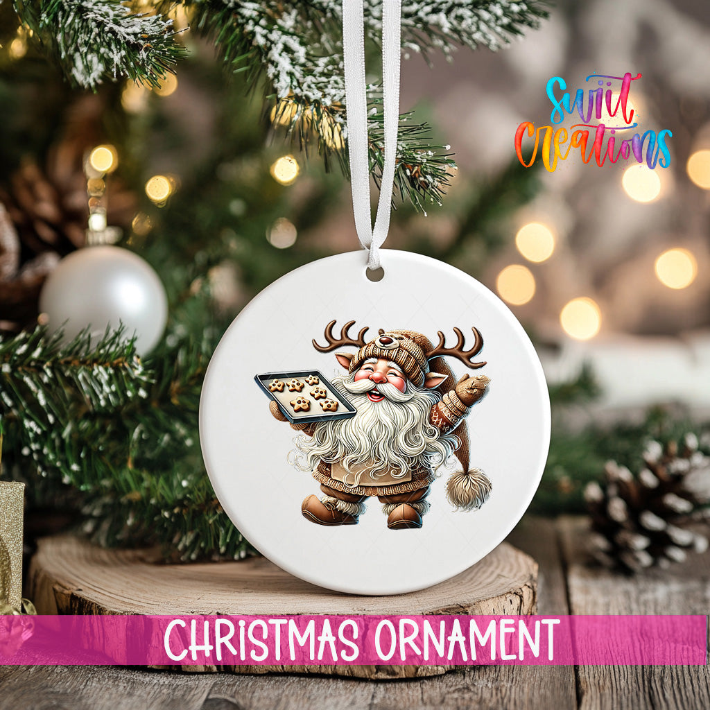 A white Christmas ornament featuring a smiling Santa Claus holding a tray of cookies, hanging from a tree branch with a ribbon.