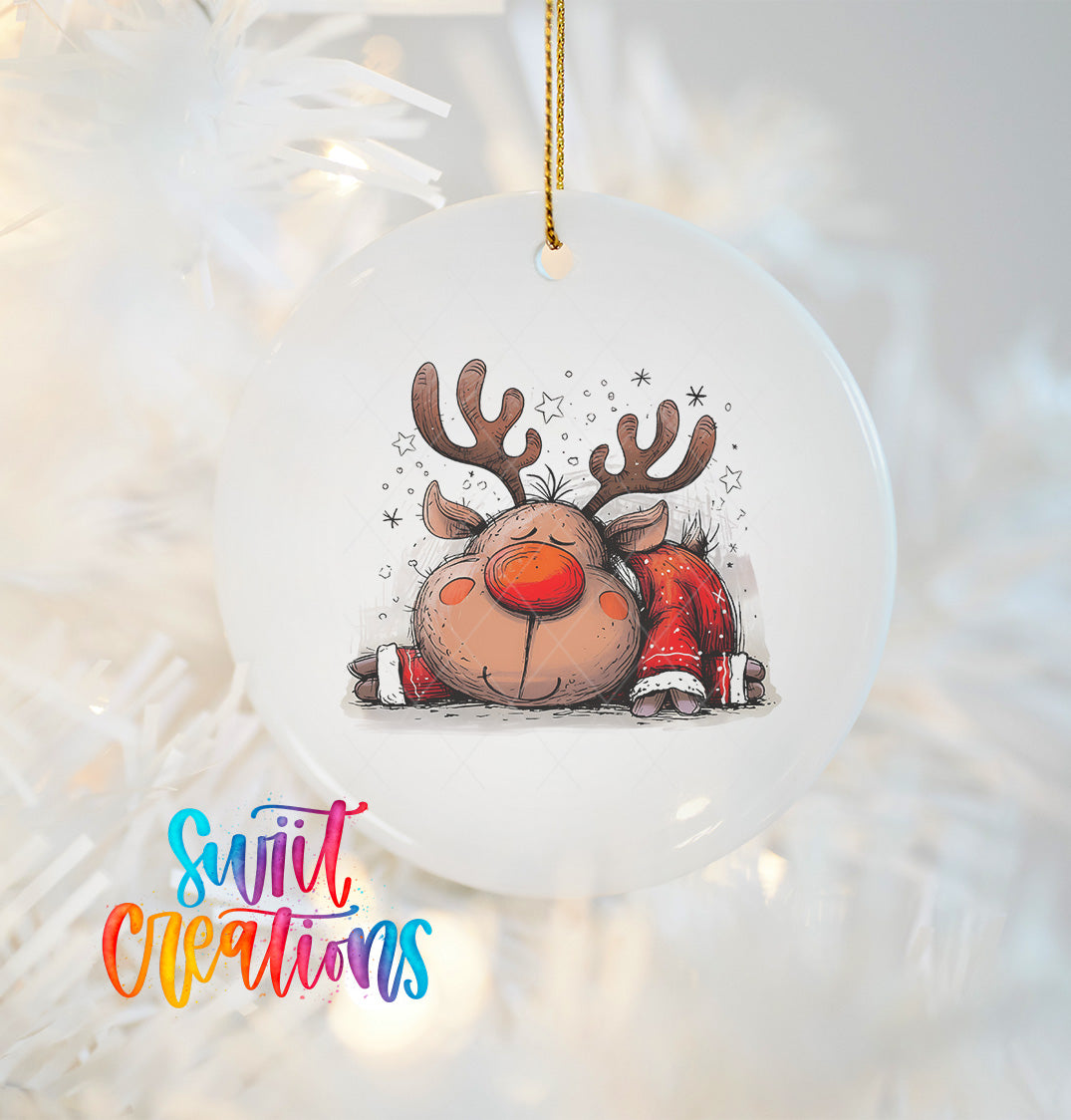 A white ornament with a cartoon image of a smiling reindeer with antlers and a red nose, hanging on a string.
