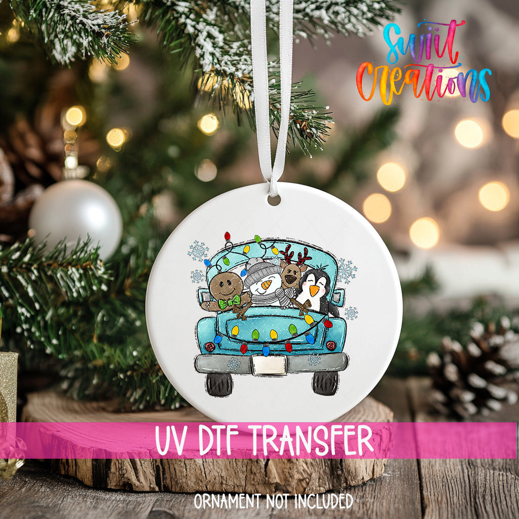 A white ceramic ornament with a cartoon illustration of a truck carrying a snowman, reindeer, and penguin, along with the text "UV Dtf Transfer" and "Ornamment not included".