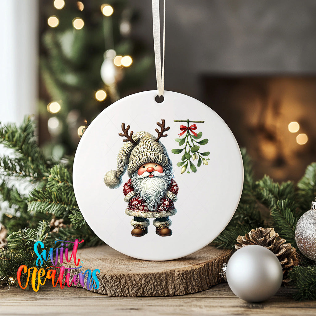 A white ornament featuring a gnome with antlers and a mistletoe is displayed on a wooden surface, surrounded by Christmas decorations and greenery.
