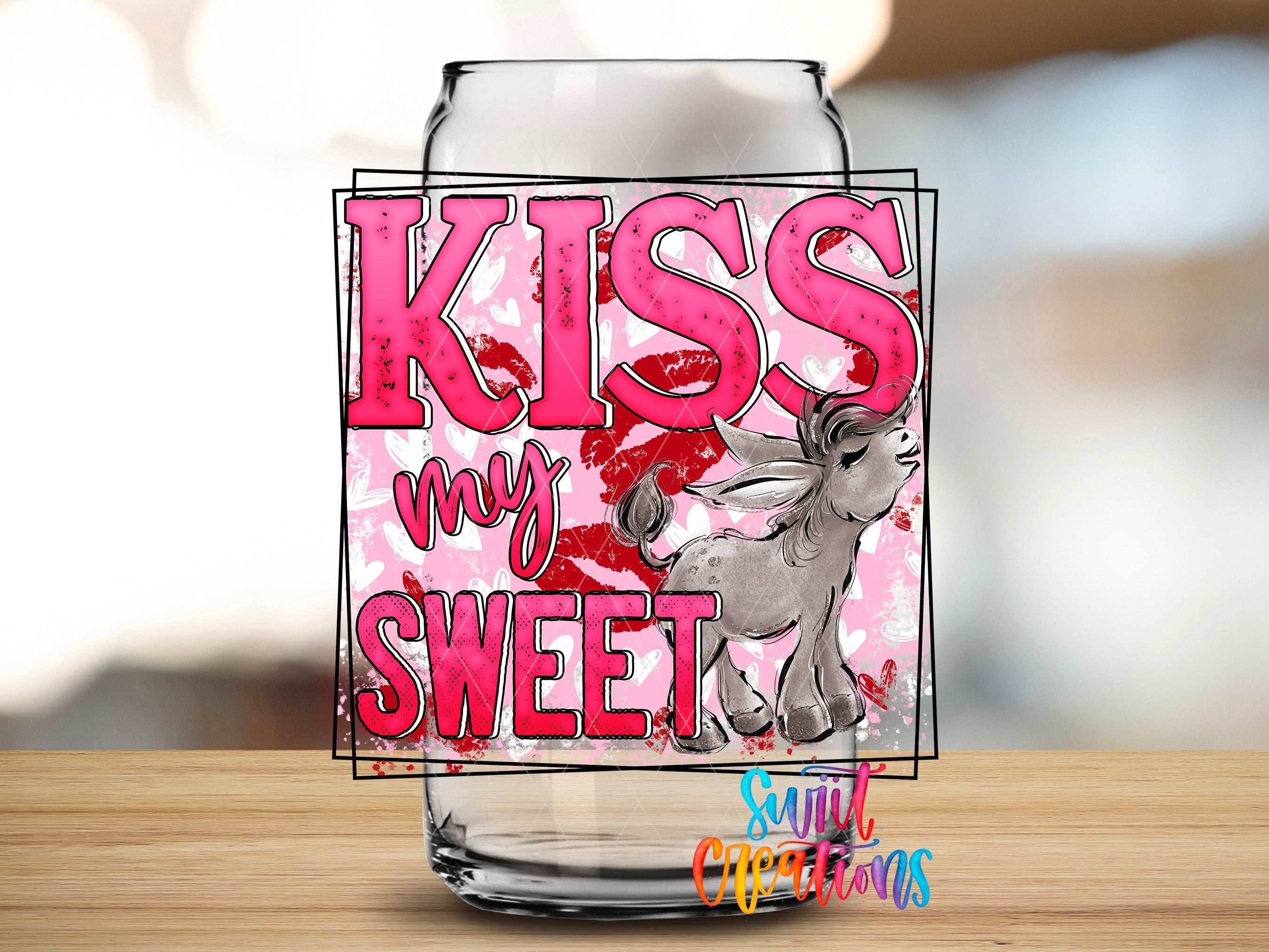 A glass jar with a pink and red design featuring the text "KISS my sweet" and an illustration of a small animal, likely a dog, with its tongue sticking out.