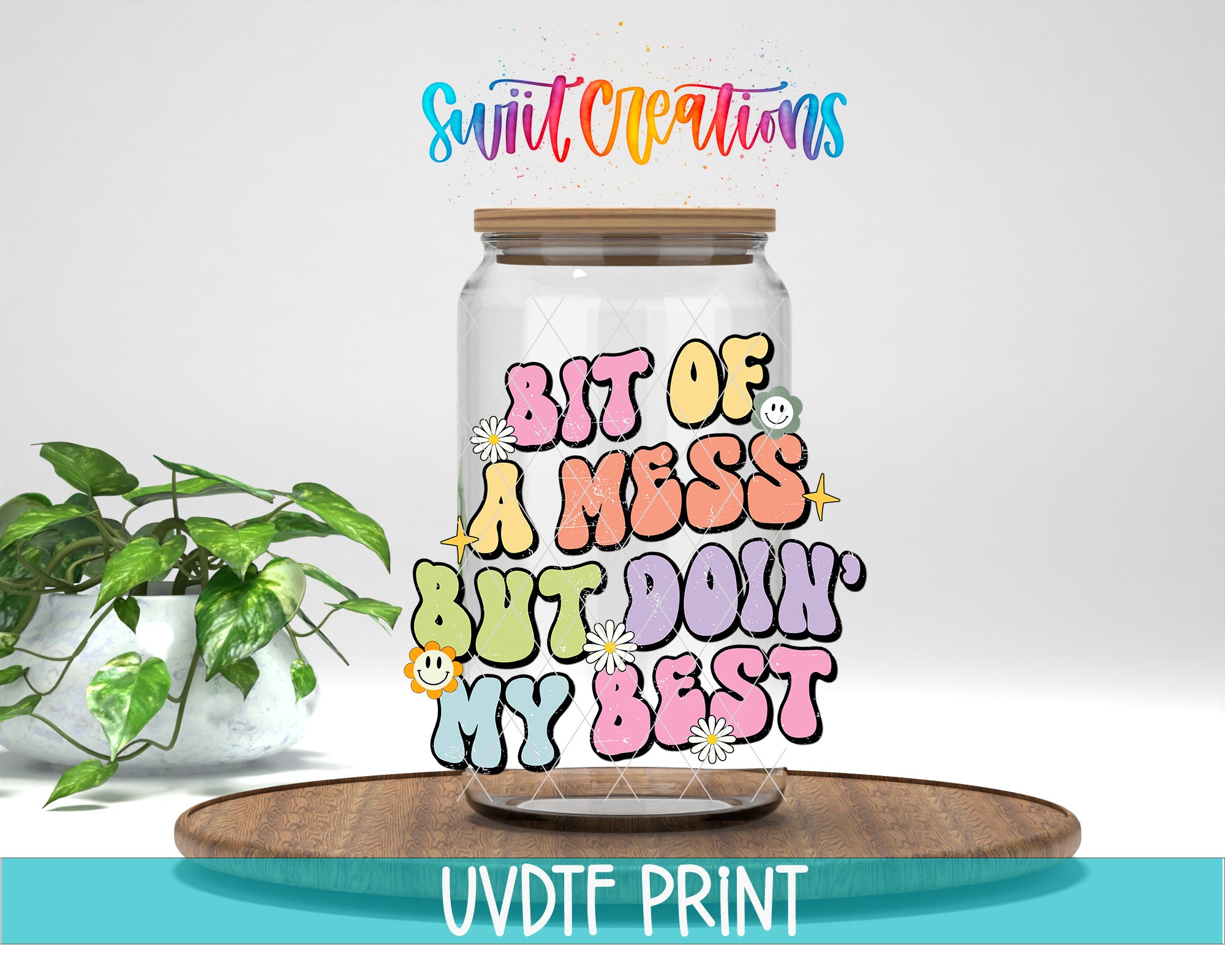 a glass jar with a colorful, whimsical design on it, placed on a wooden surface. The jar has a lid and is surrounded by a potted plant. The text on the jar reads "Bit of a mess but doin' my best".