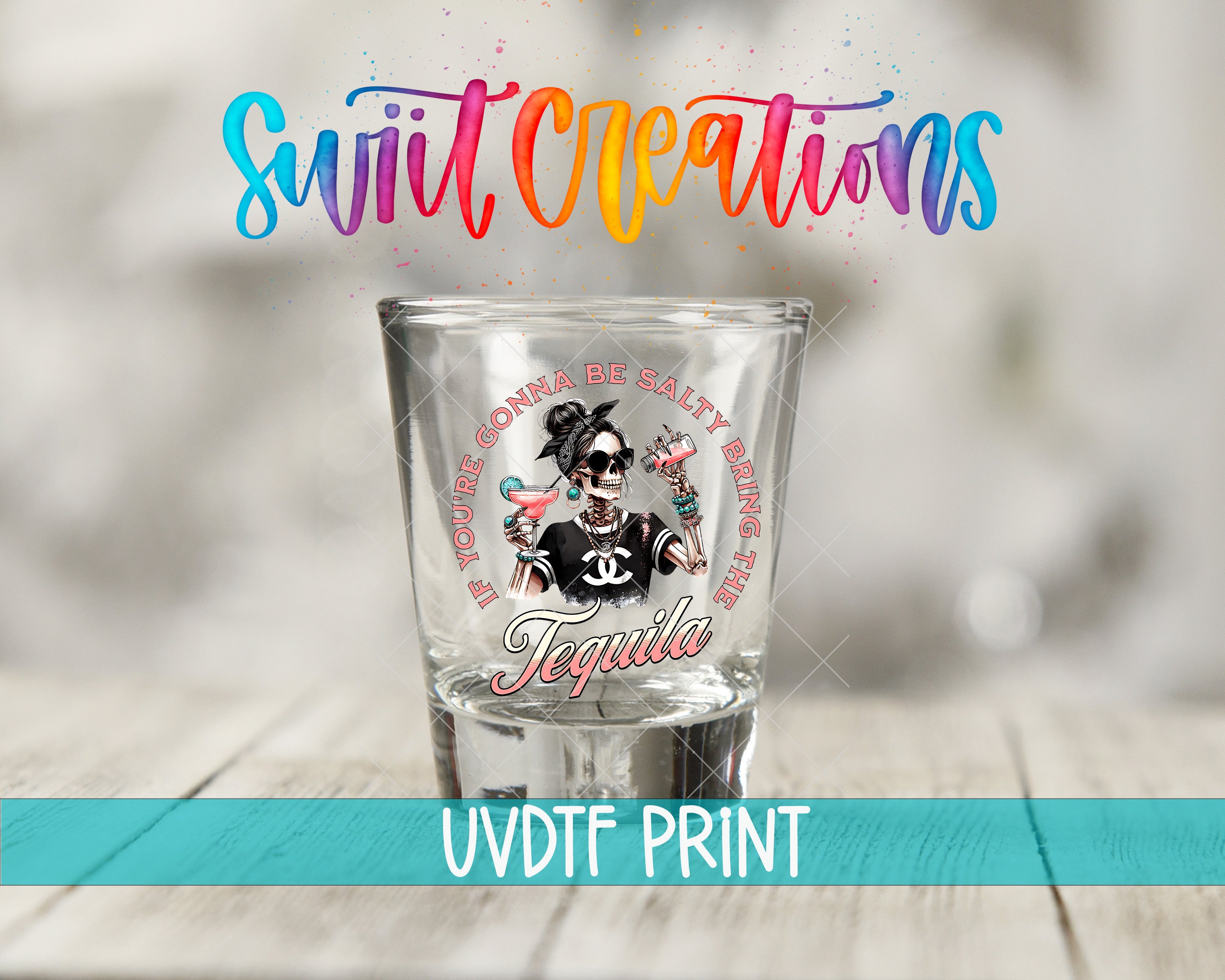 A shot glass with a colorful design and text printed on it, placed on a wooden surface.
