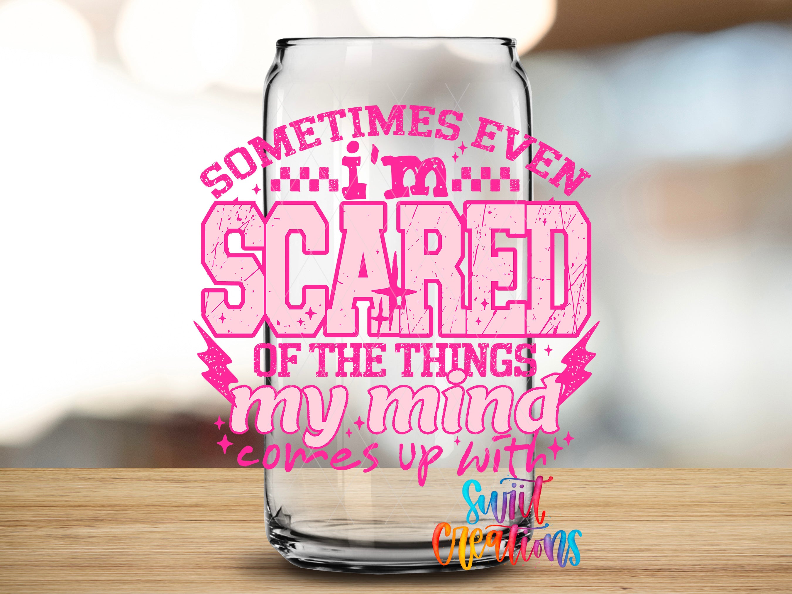a glass can with a text design on it, placed on a wooden surface.