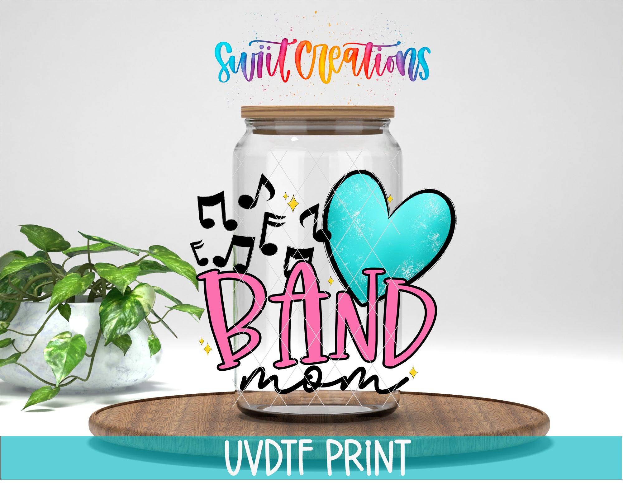 a glass jar with a heart and musical notes, along with the text "BAND mom" and "Swift Creations" written on it. The jar is placed on a wooden surface, and there is a potted plant in the background.