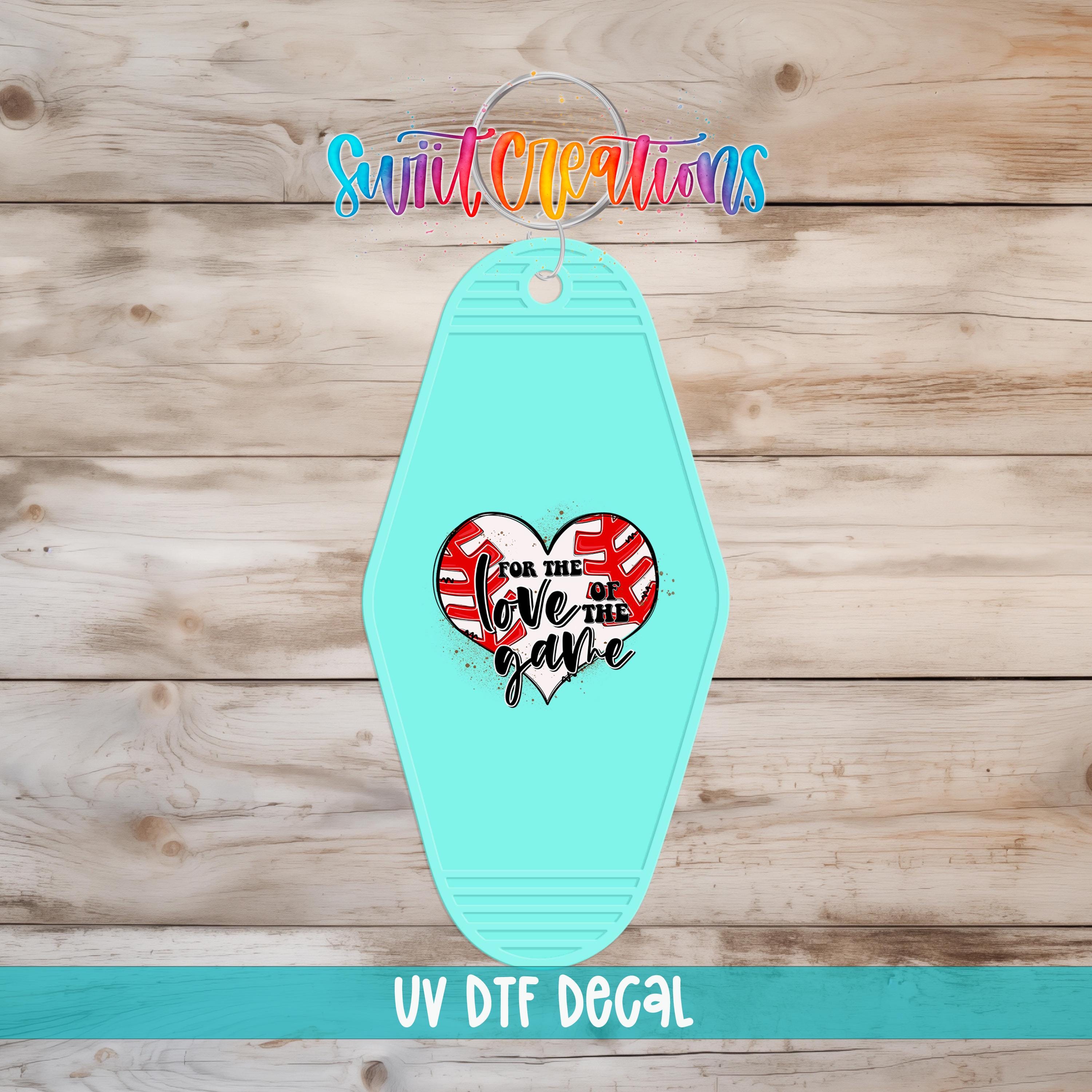 A turquoise keychain with a heart-shaped design and text on it, placed on a wooden surface.