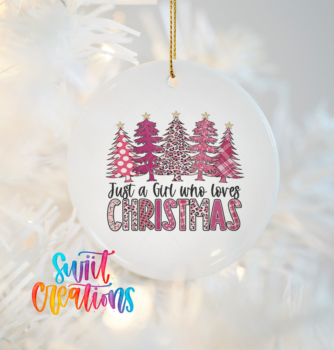 A white Christmas ornament with a design of pink and white trees, along with the text "Just a Girl who loves Christmas" printed on it.