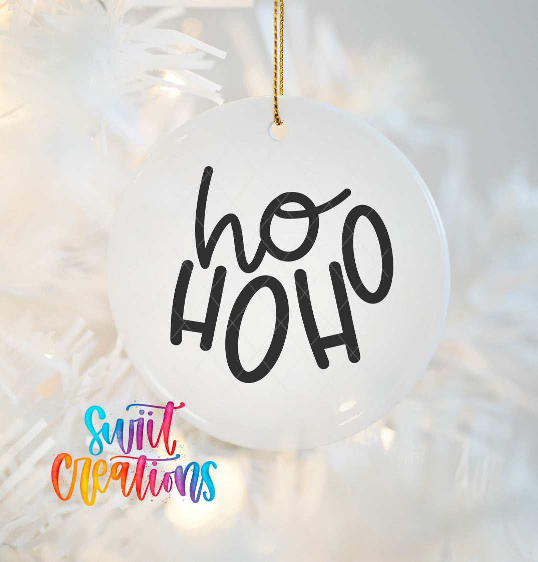 A white ornament with the text "ho ho" in black cursive letters hanging from a string.