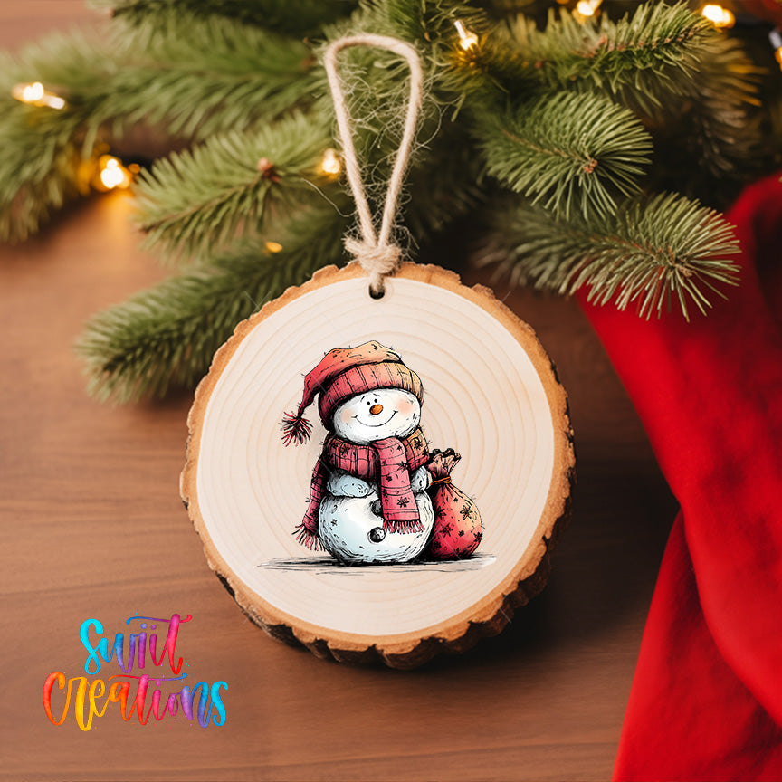 A wooden ornament featuring a snowman is hanging on a Christmas tree, surrounded by pine branches and twinkling lights.