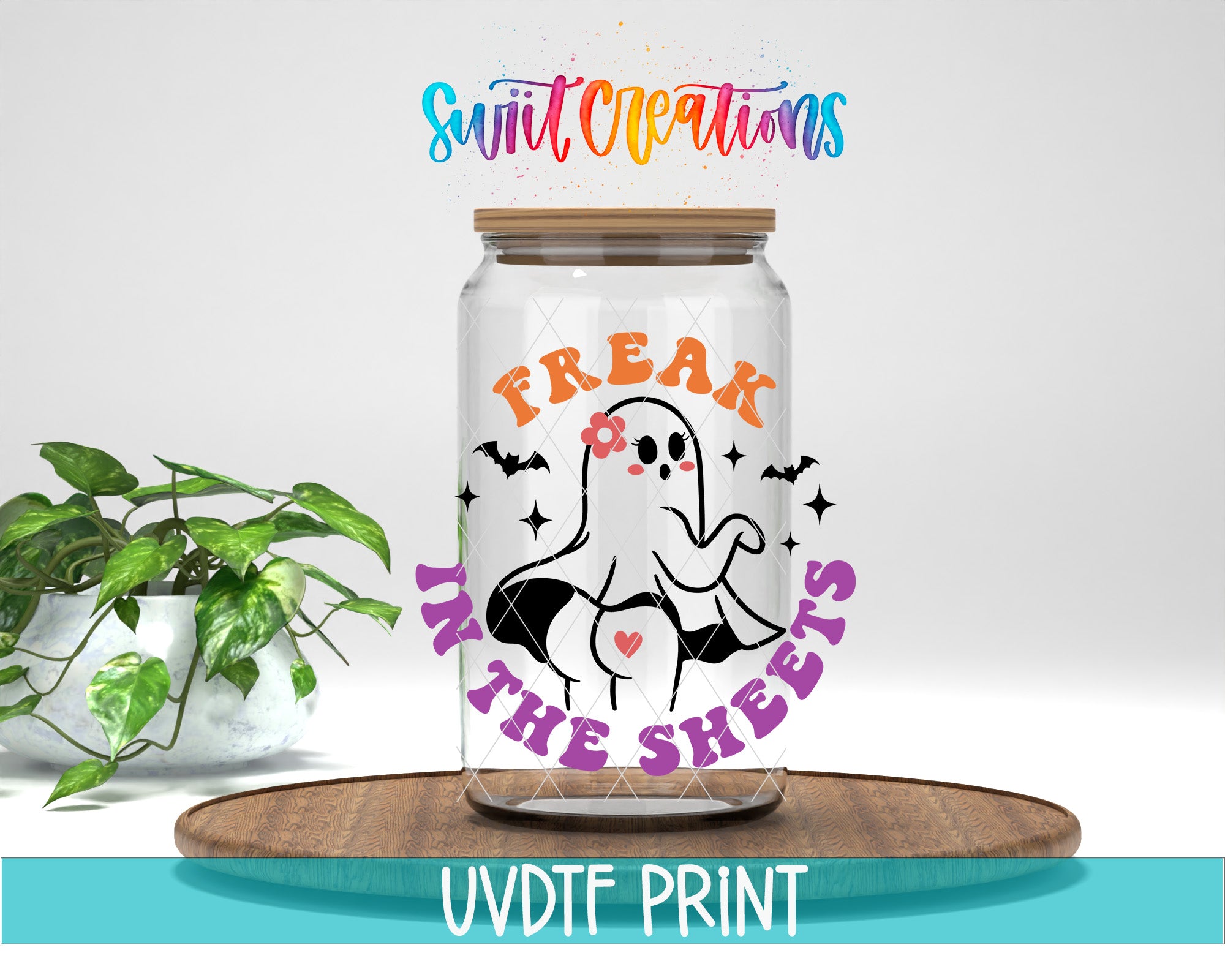 a glass jar with a Halloween-themed design, including a ghost and the text "FREAK IN THE SHEETS". The jar is placed on a wooden surface, and there is a potted plant in the background.