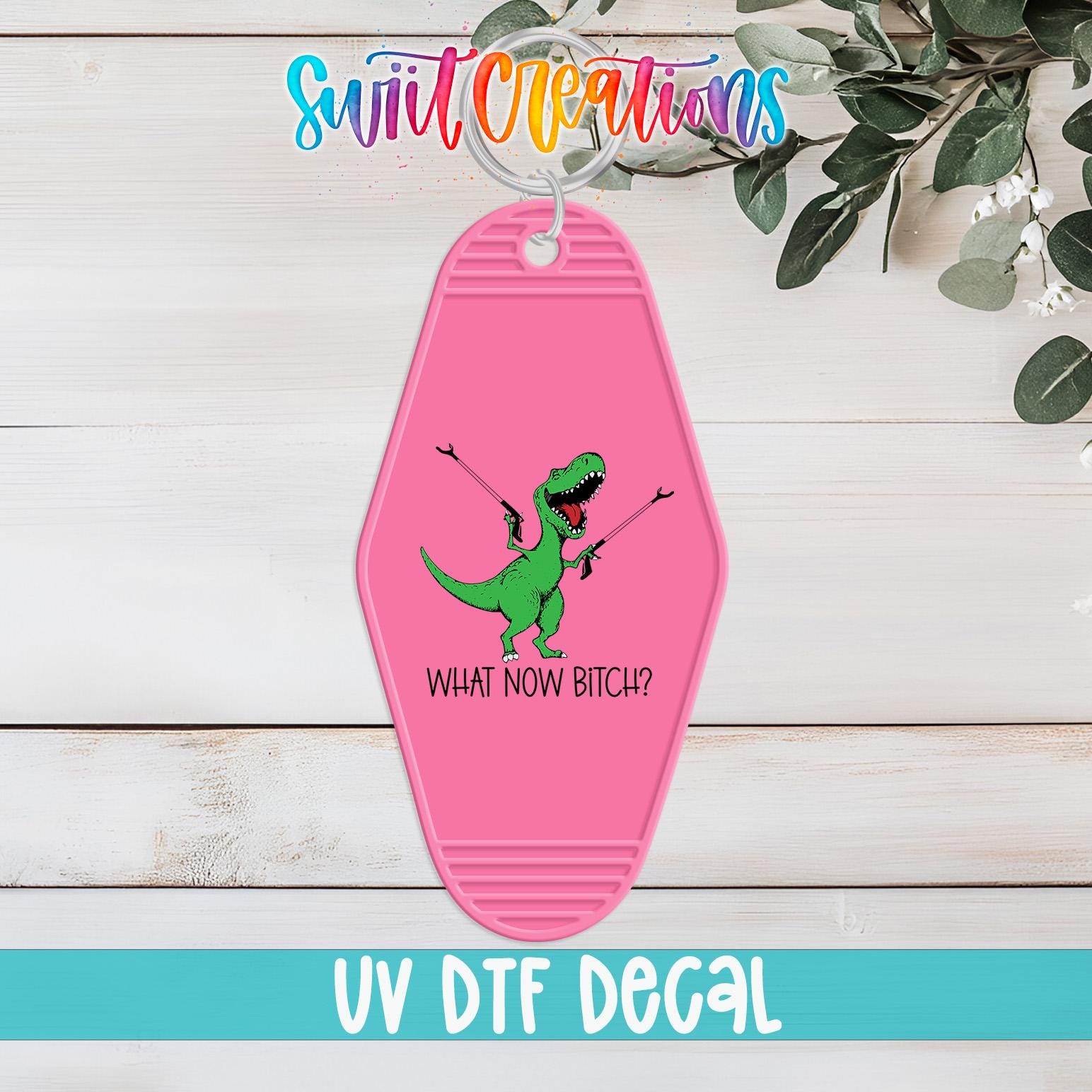 A pink keychain with a cartoon dinosaur and the text "WHAT NOW BITCH?" printed on it, along with the text "UV Dtf Decal" at the bottom.