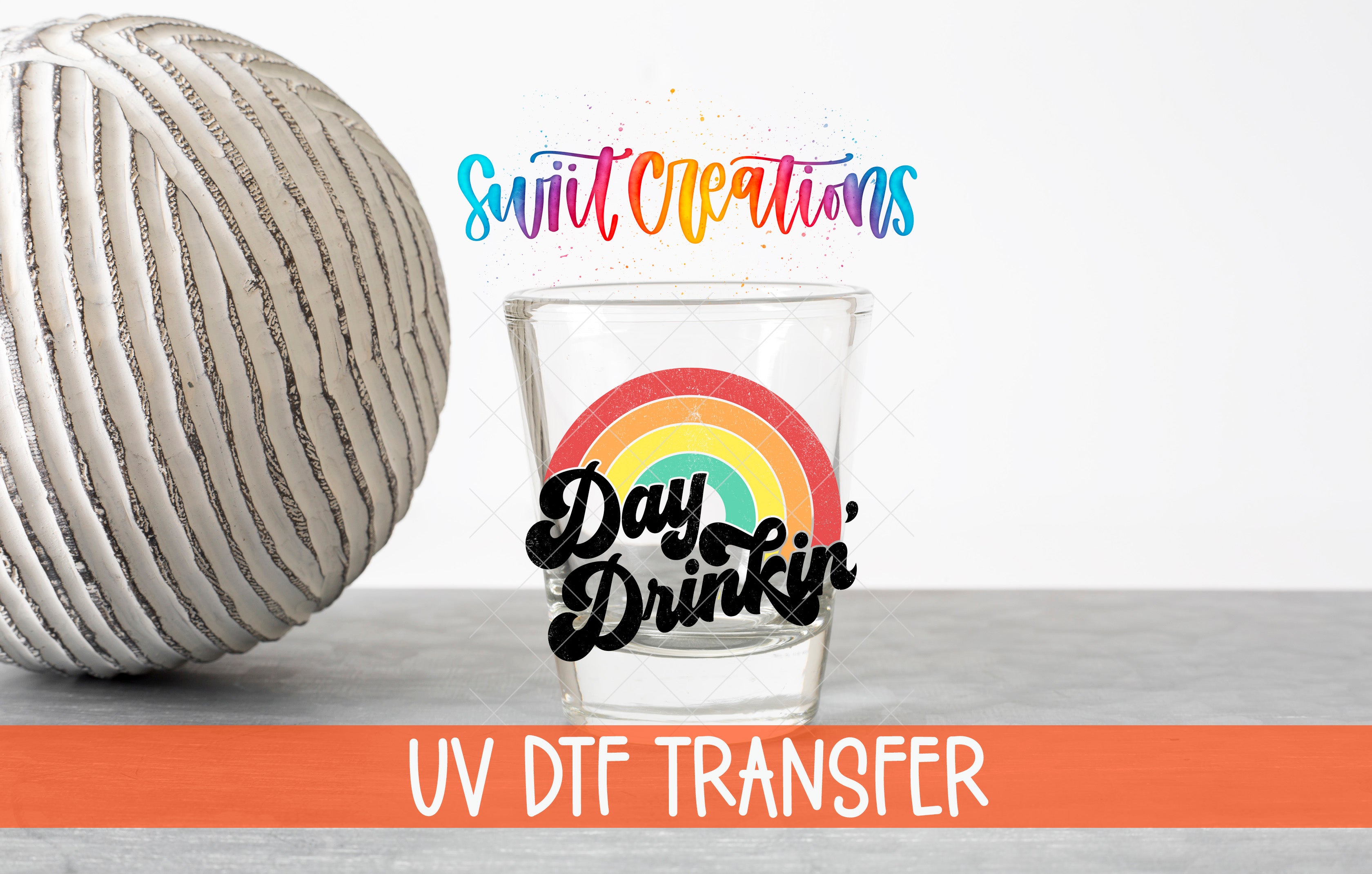 a glass with a rainbow design and the text "Day Drinkin'" on it, along with a gray ball and the text "Swift Creations" and "UV Dtf Transfer" in the background.