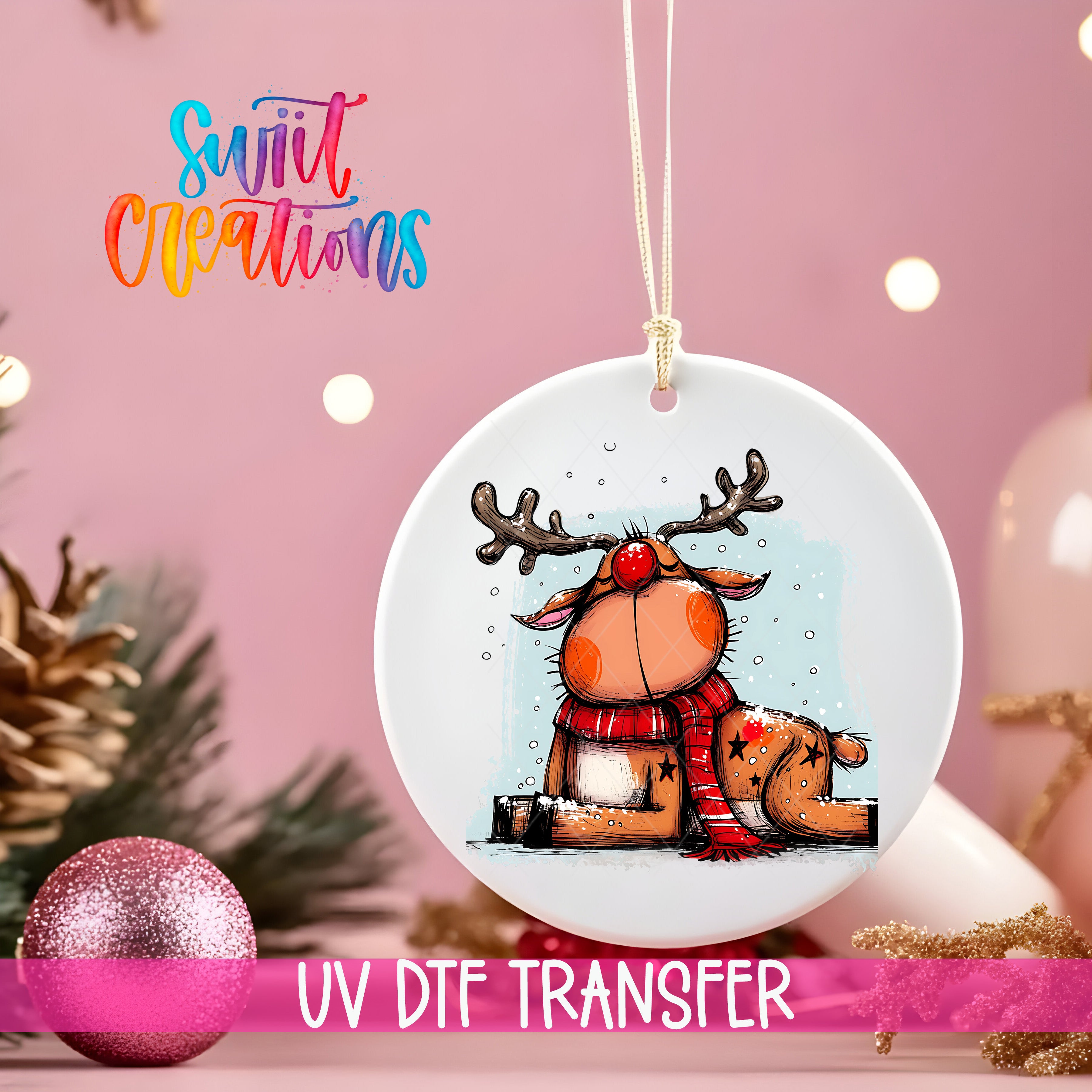 A white ornament with a cartoon reindeer and a red nose, hanging on a string against a pink background with Christmas decorations.